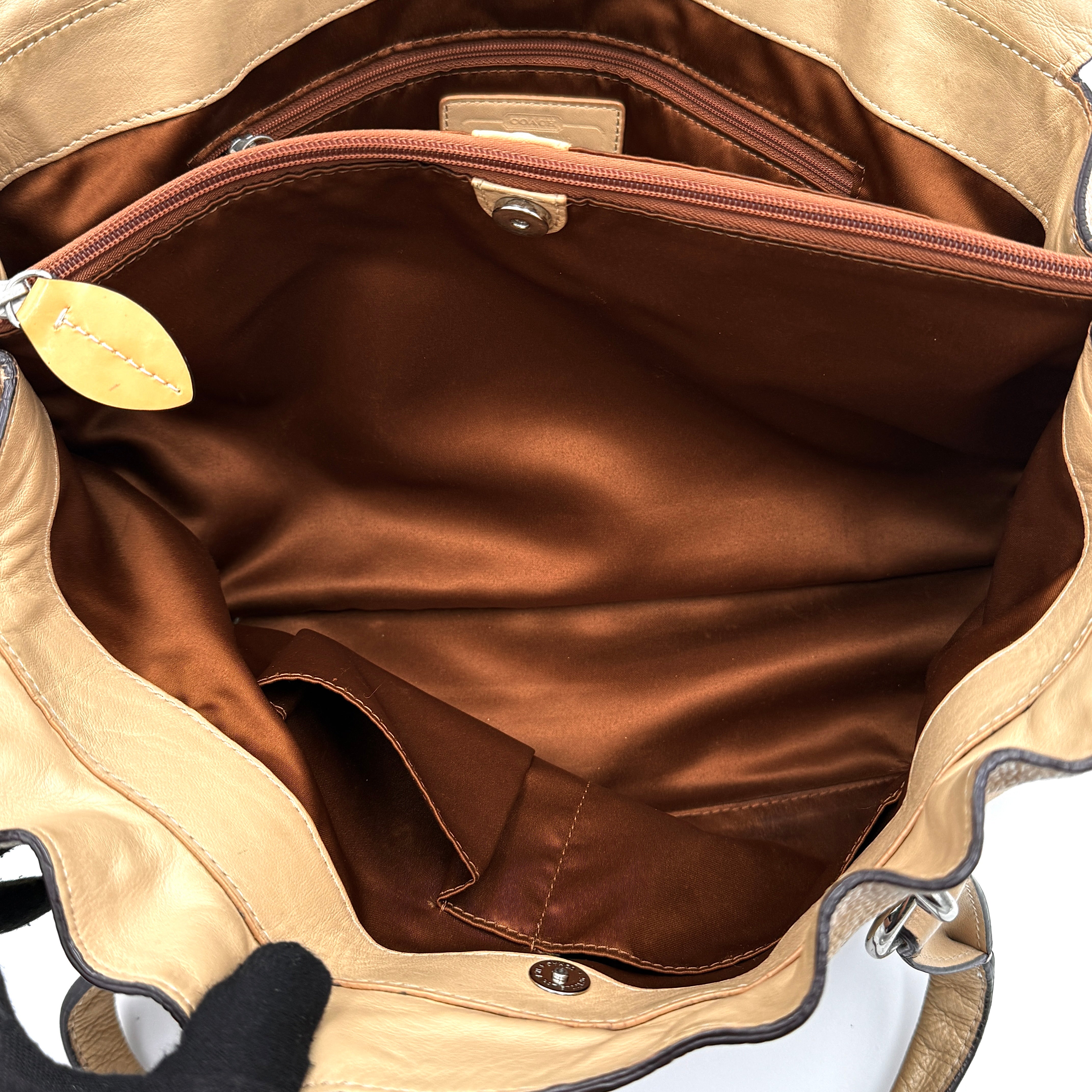 Coach Penelope handbag in cream pebble leather with rolled handles and silver-tone hardware against a white background.