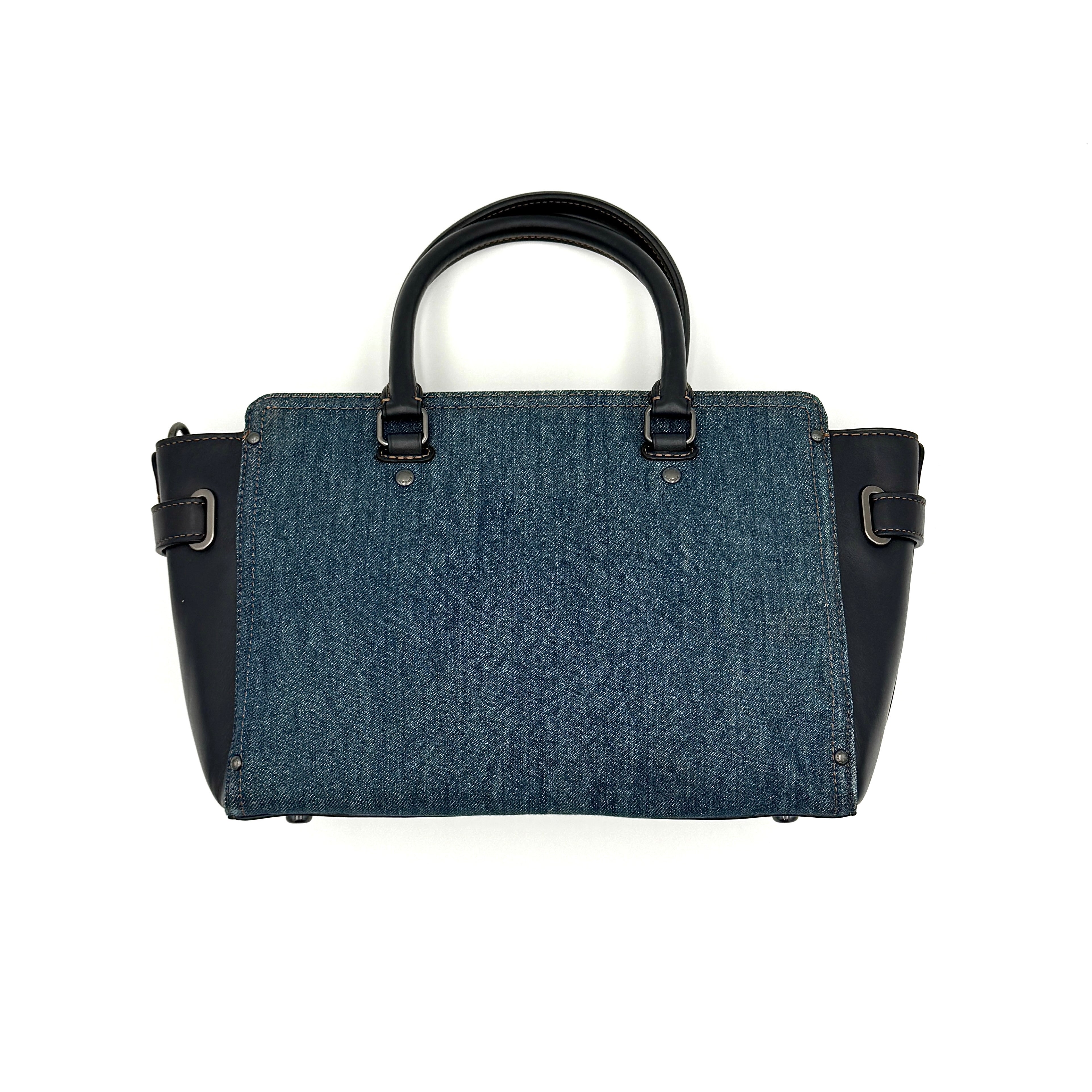 Coach Swagger 27 handbag in blue denim with navy leather trim and detachable strap, featuring prominent double turn-lock hardware and floral interior.
