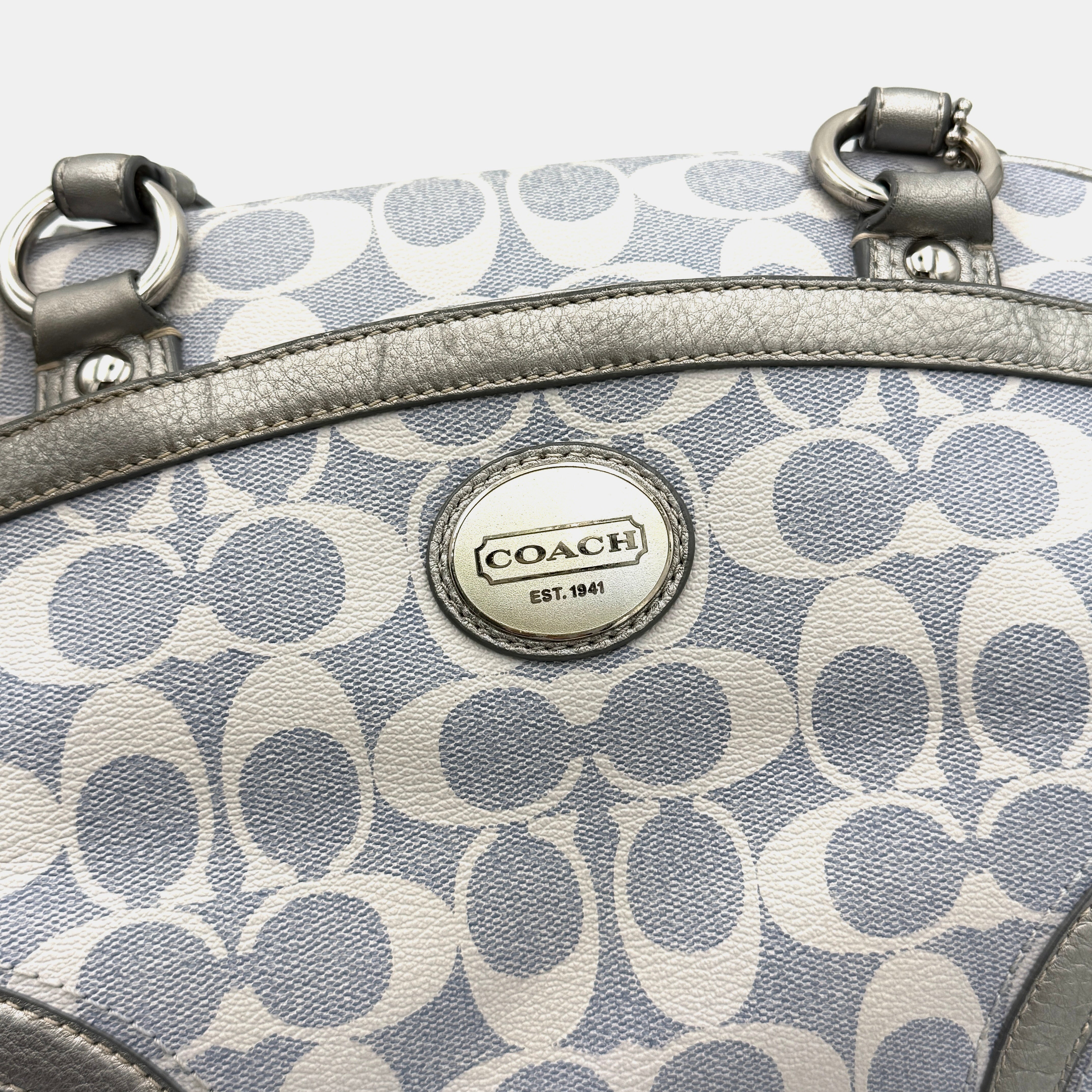 Coach Signature Peyton Satchel in light blue and grey canvas with metallic leather trim and double handles, shown against a white background.