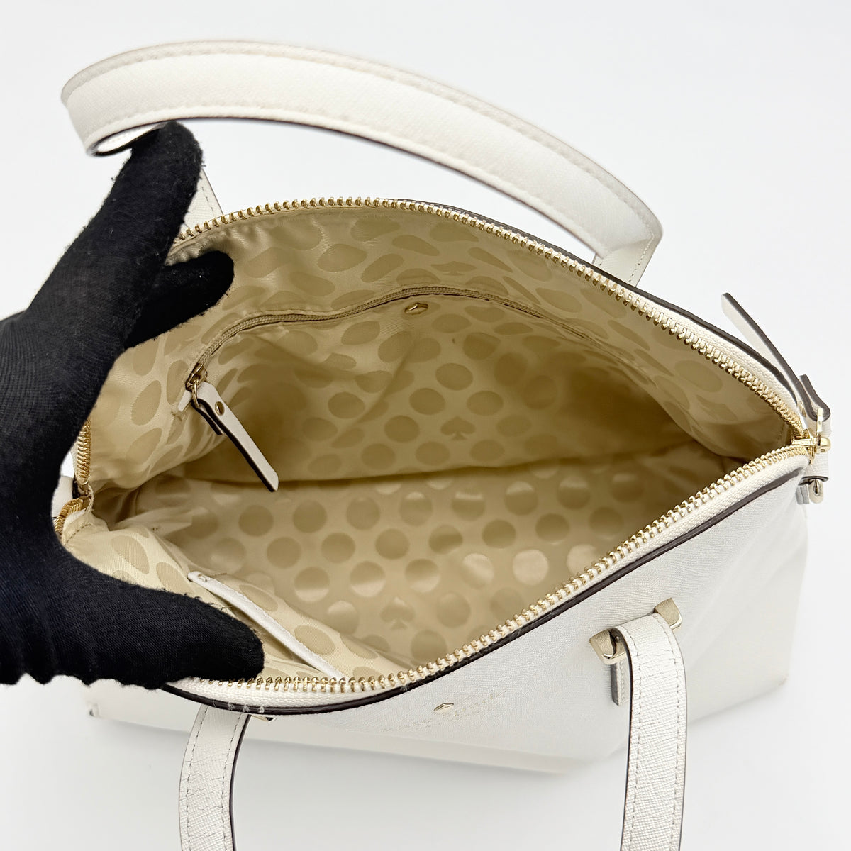 Top view of the Kate Spade Cedar Street Maise satchel in ivory, showing its spacious polka dot interior and zip pocket detail.