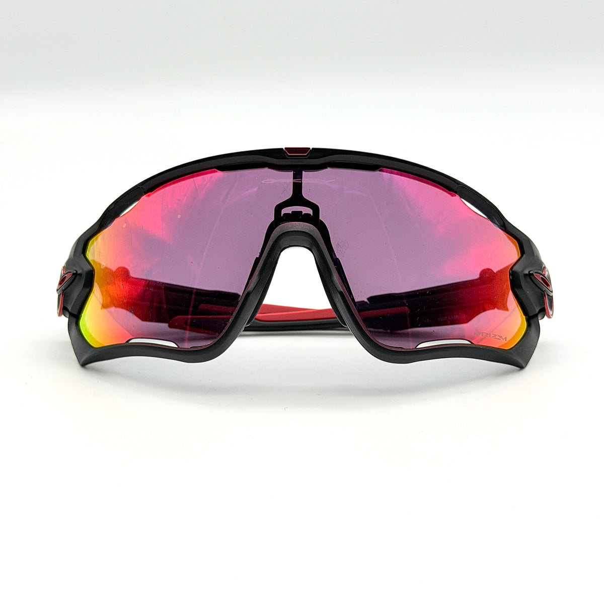 Oakley Jawbreaker Prizm sunglasses in matte black and red with pink-red Prizm lenses, shown with a black Oakley hard case and extra nose pad.