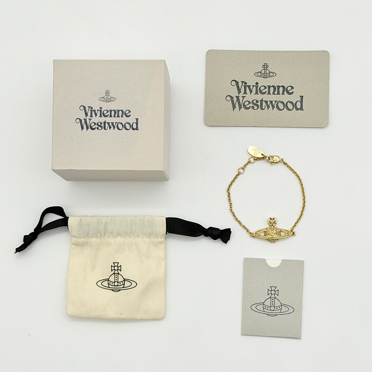 Vivienne Westwood gold rhinestone Orb bracelet with original box, dust bag, and authenticity card arranged on a white background.