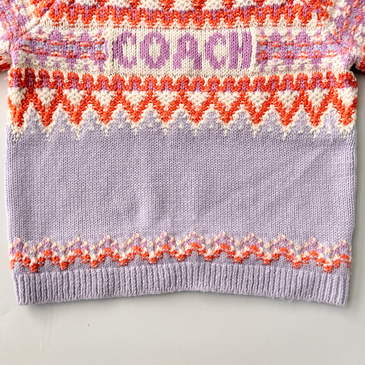Coach Fair Isle Ski Sweater in lilac with orange and cream geometric pattern and COACH logo across the chest.