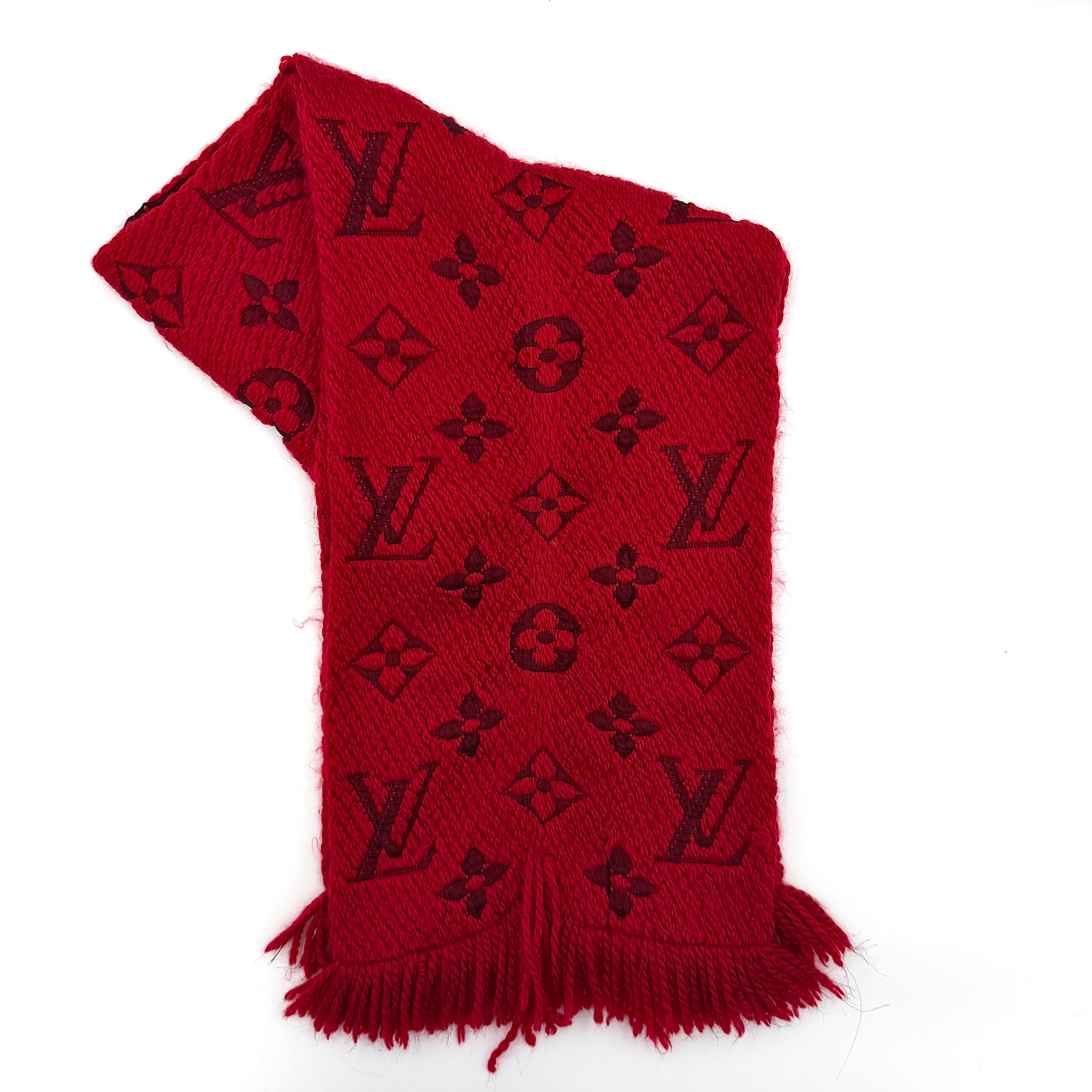 A luxurious Louis Vuitton Monogram Echarpe wool scarf in vibrant red, distinguished by its chunky texture, signature monogram pattern, and playful fringe edging.