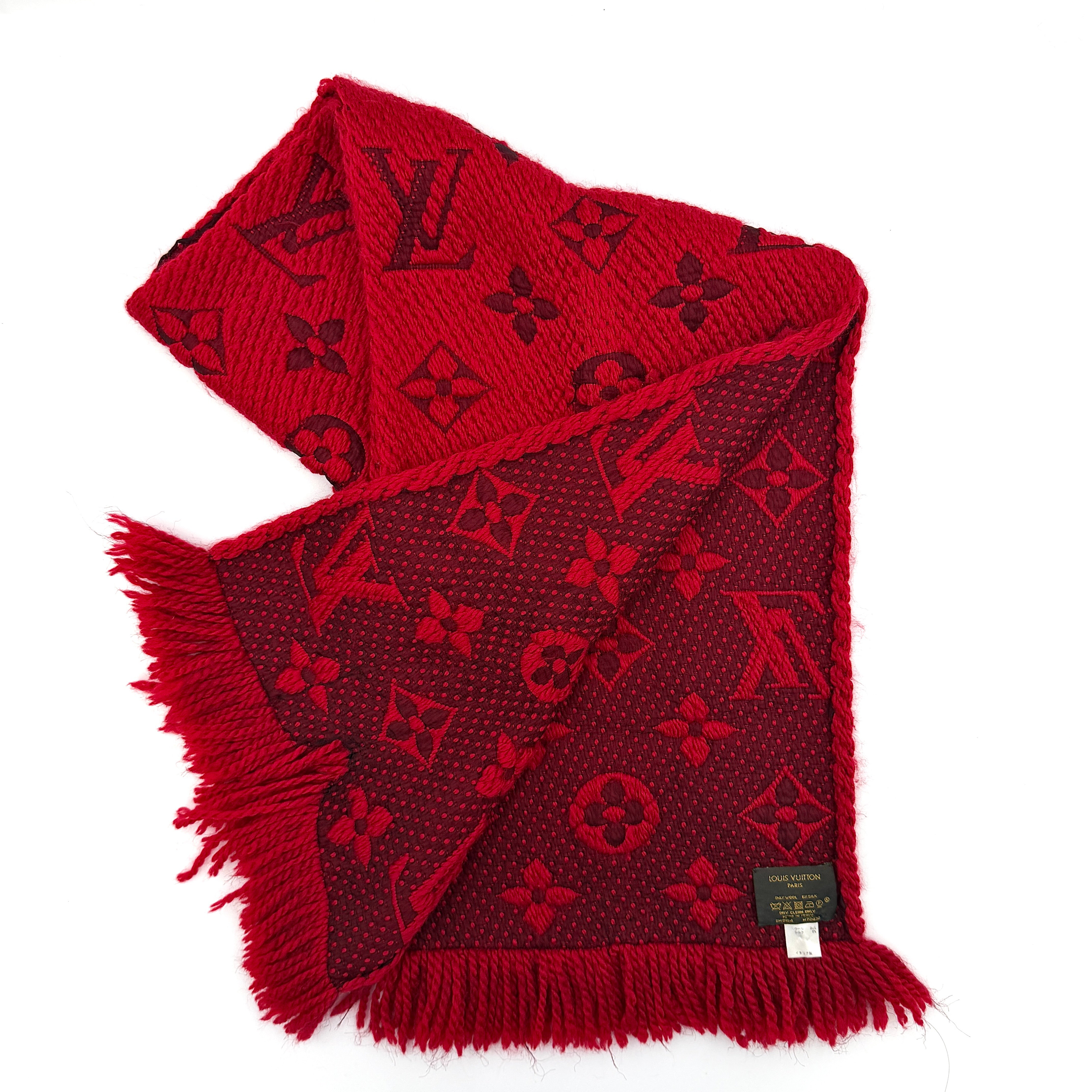 A luxurious Louis Vuitton Monogram Echarpe wool scarf in vibrant red, distinguished by its chunky texture, signature monogram pattern, and playful fringe edging.