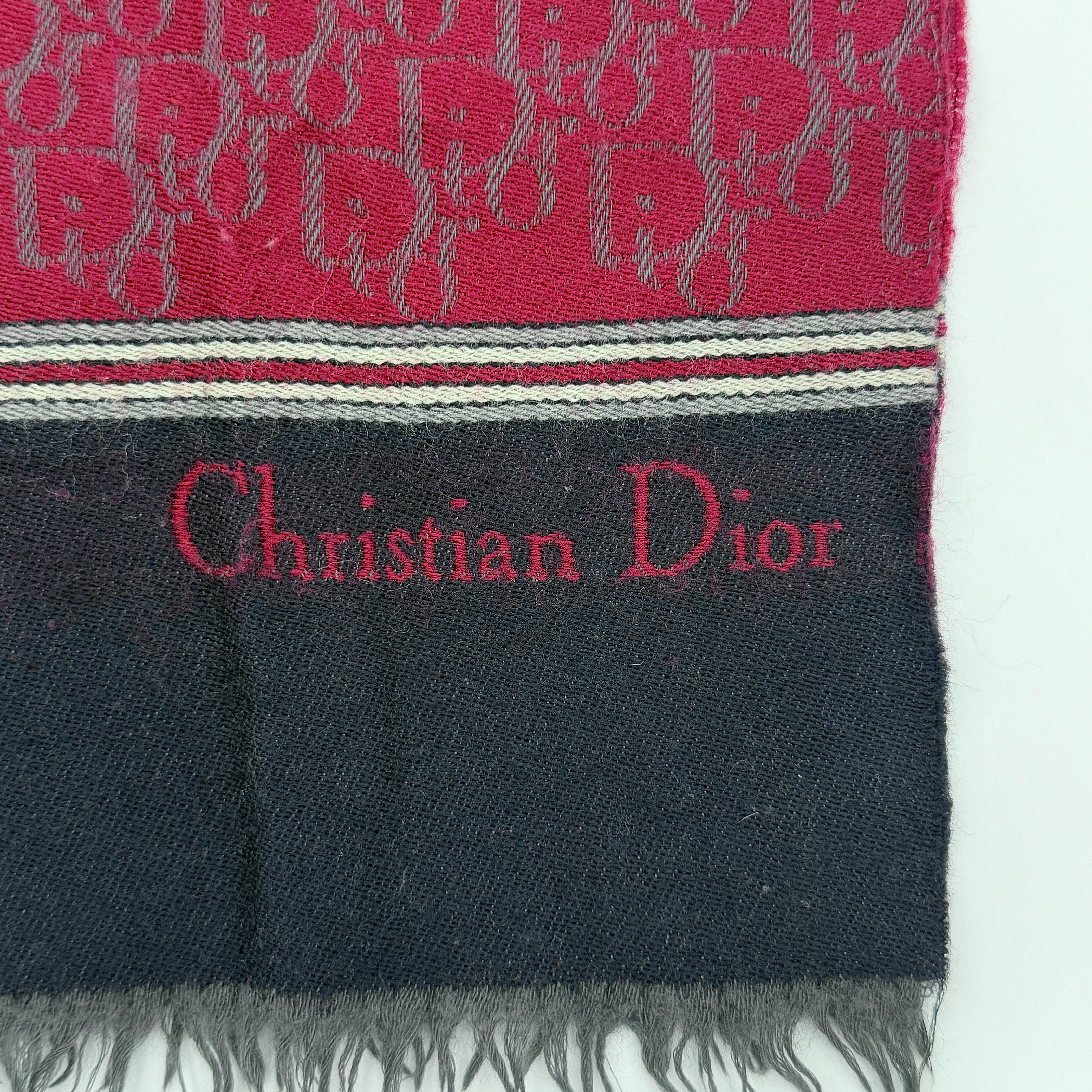 A red Dior Oblique Trotter wool scarf with all-over monogram pattern, navy border, stripe detail, and fringe trim.