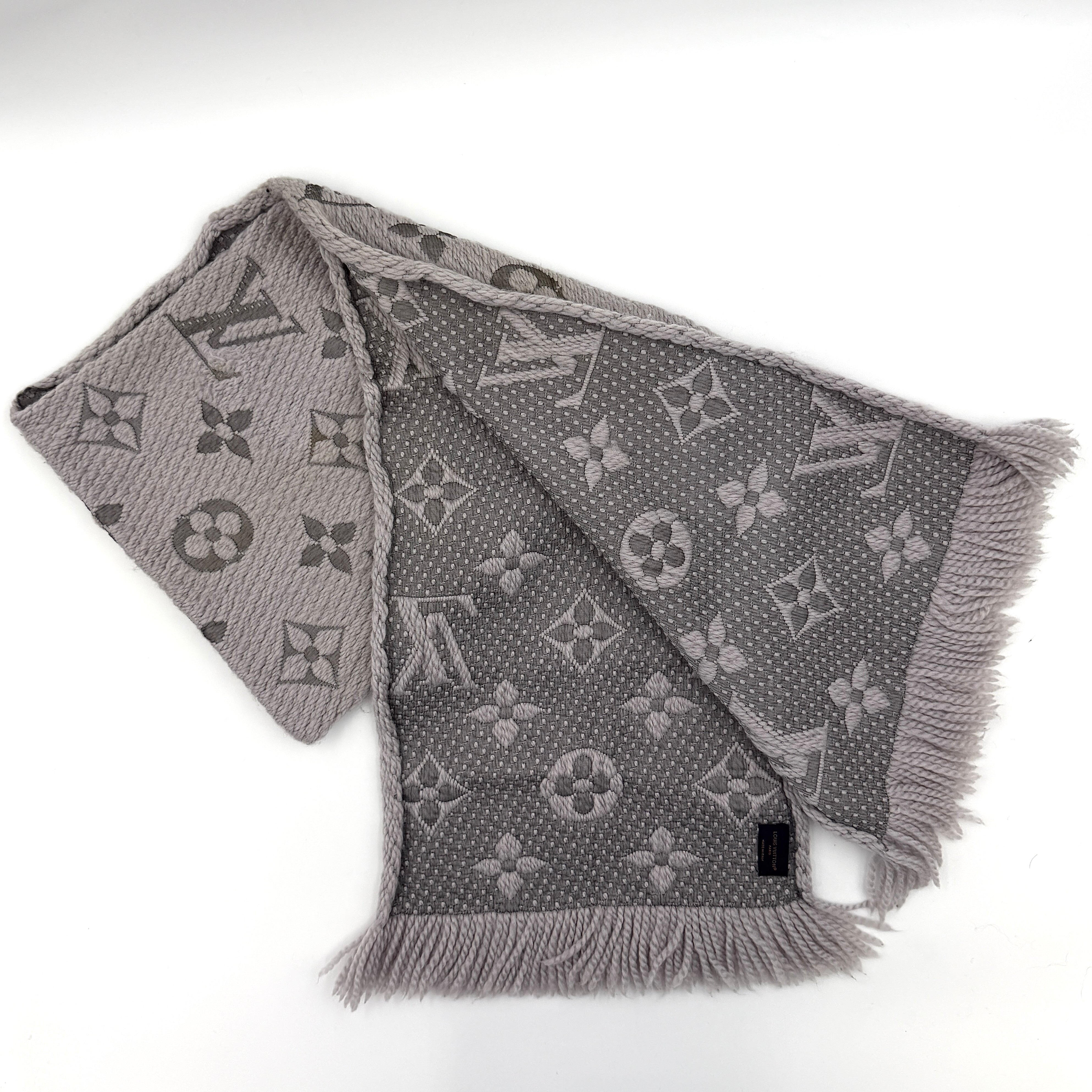 Louis Vuitton grey wool scarf featuring an all-over monogram pattern with soft fringed edges, elegantly draped for a premium look.