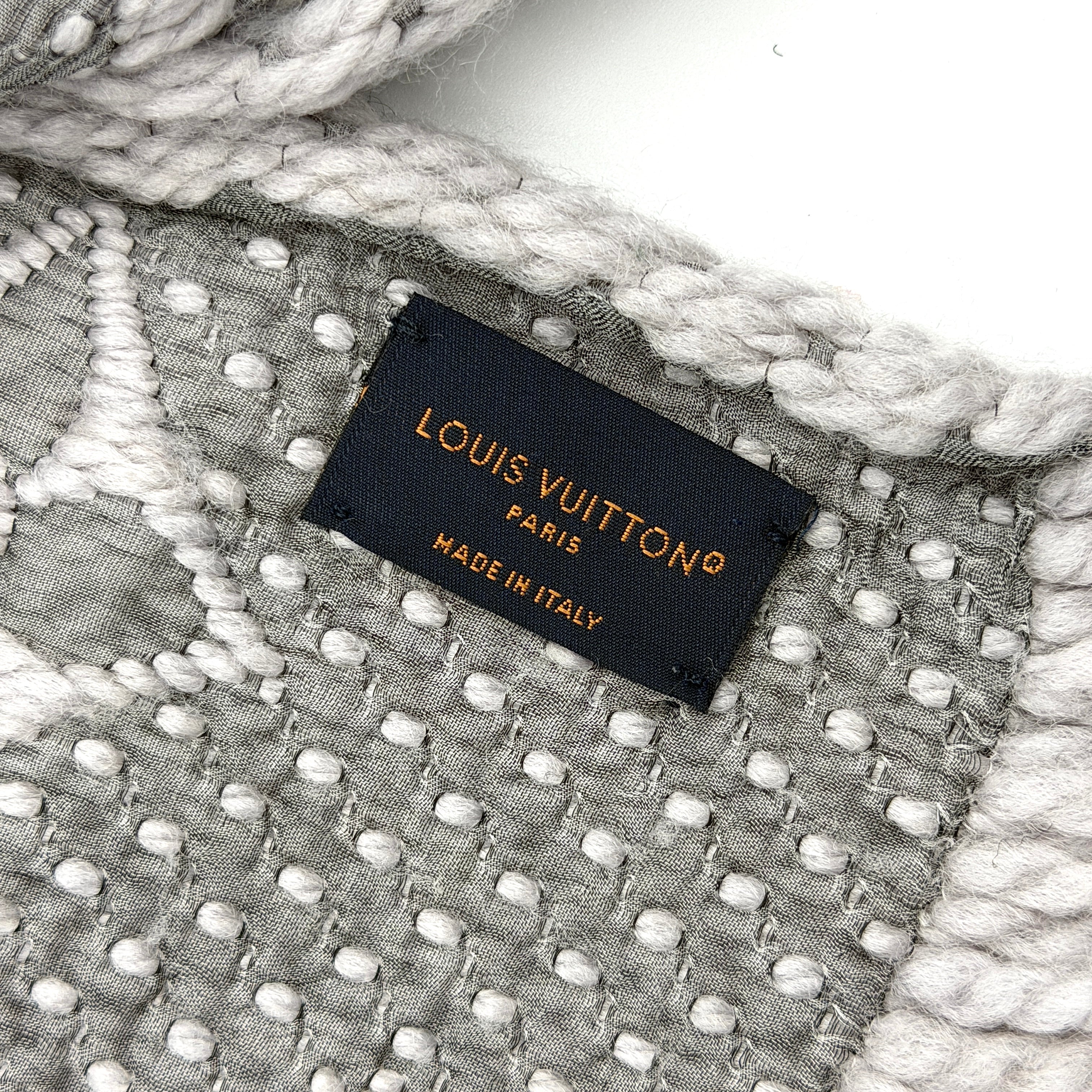 Louis Vuitton grey wool scarf featuring an all-over monogram pattern with soft fringed edges, elegantly draped for a premium look.