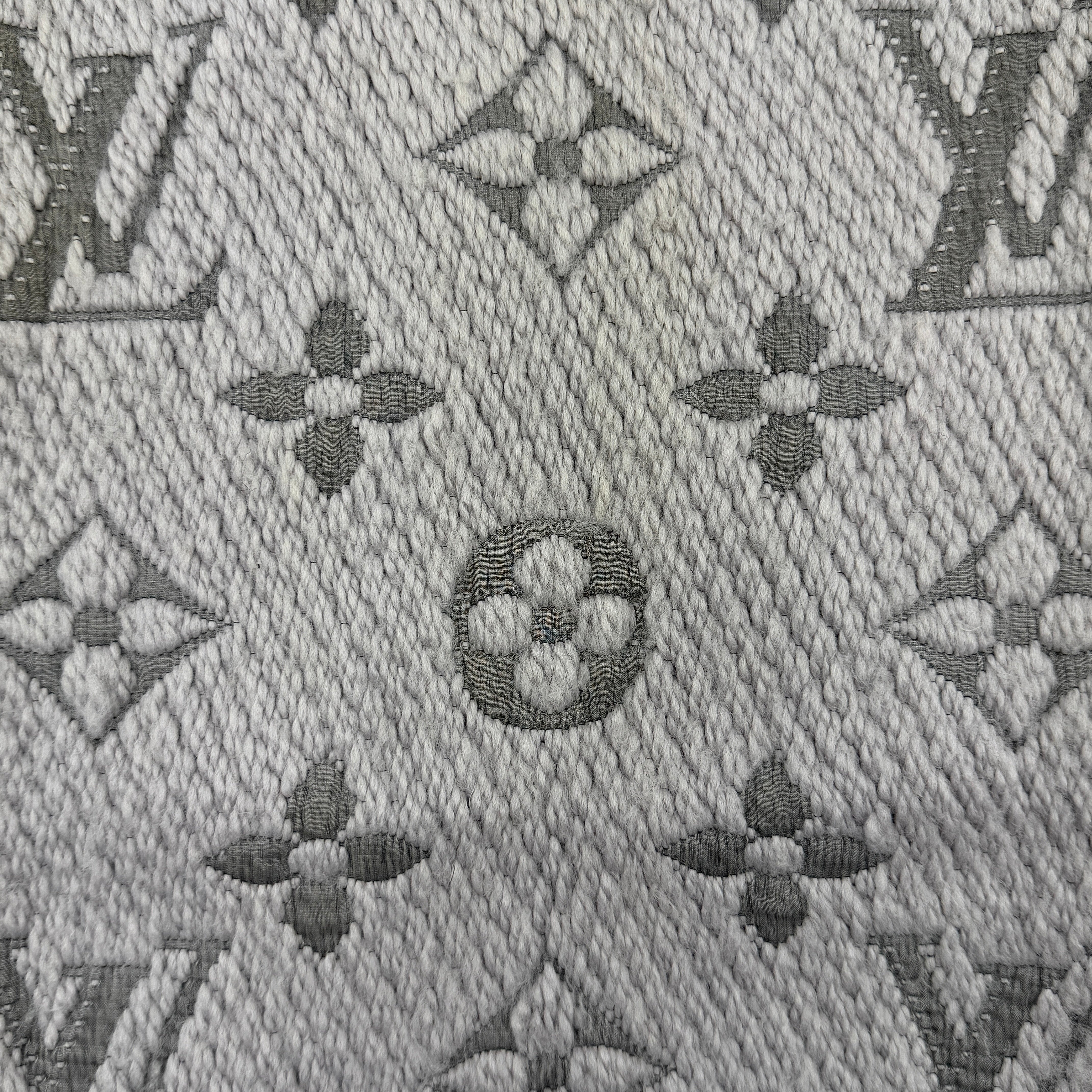 Louis Vuitton grey wool scarf featuring an all-over monogram pattern with soft fringed edges, elegantly draped for a premium look.