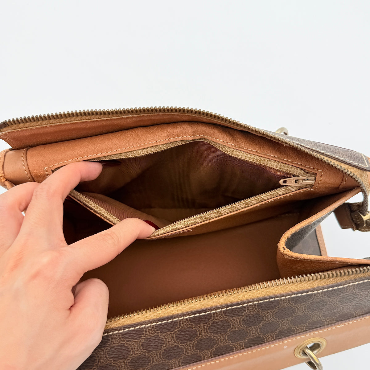Celine Macadam Triomphe shoulder bag in brown coated canvas and tan leather with gold-tone hardware shown against a white background.