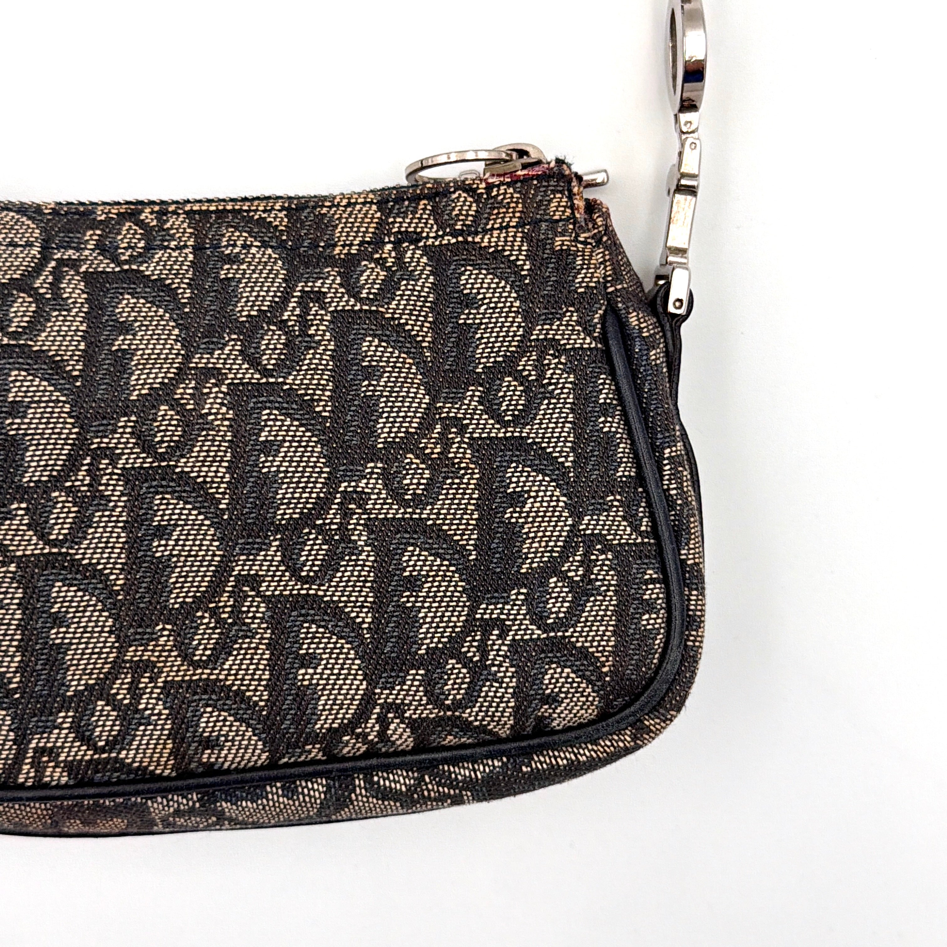Dior Trotter Charm Pochette bag in grey and navy oblique canvas, featuring bold silver-tone Dior letter charms and a black leather strap.