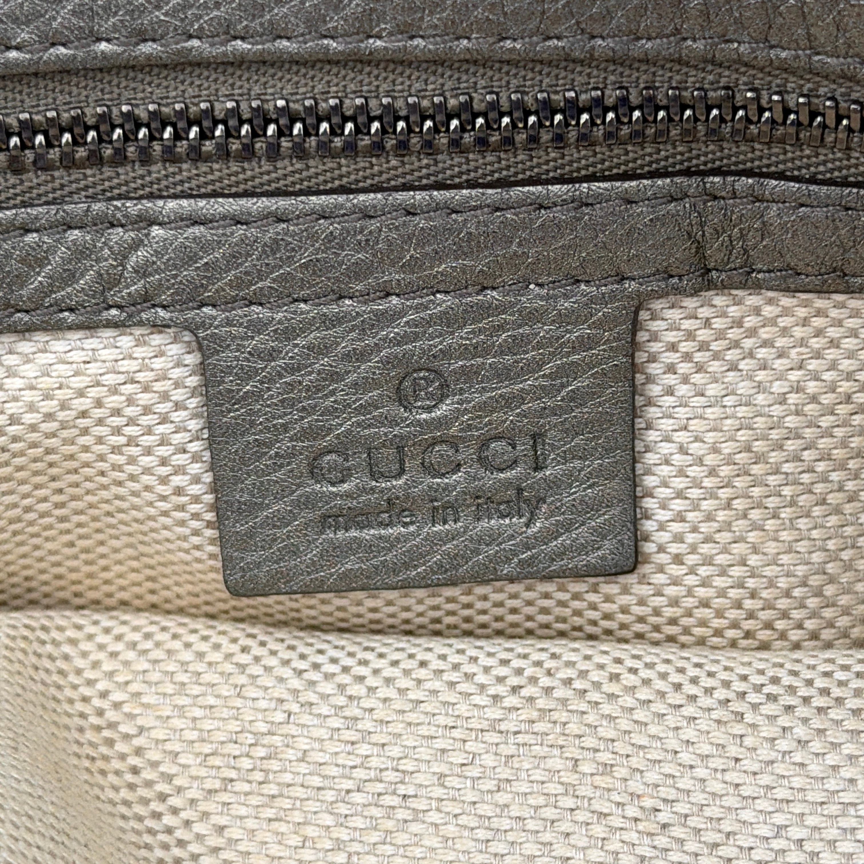 Gucci GG Soho Shoulder Bag in grey pebbled leather, featuring dual top handles, oversized stitched GG logo, and a leather tassel zip pull.