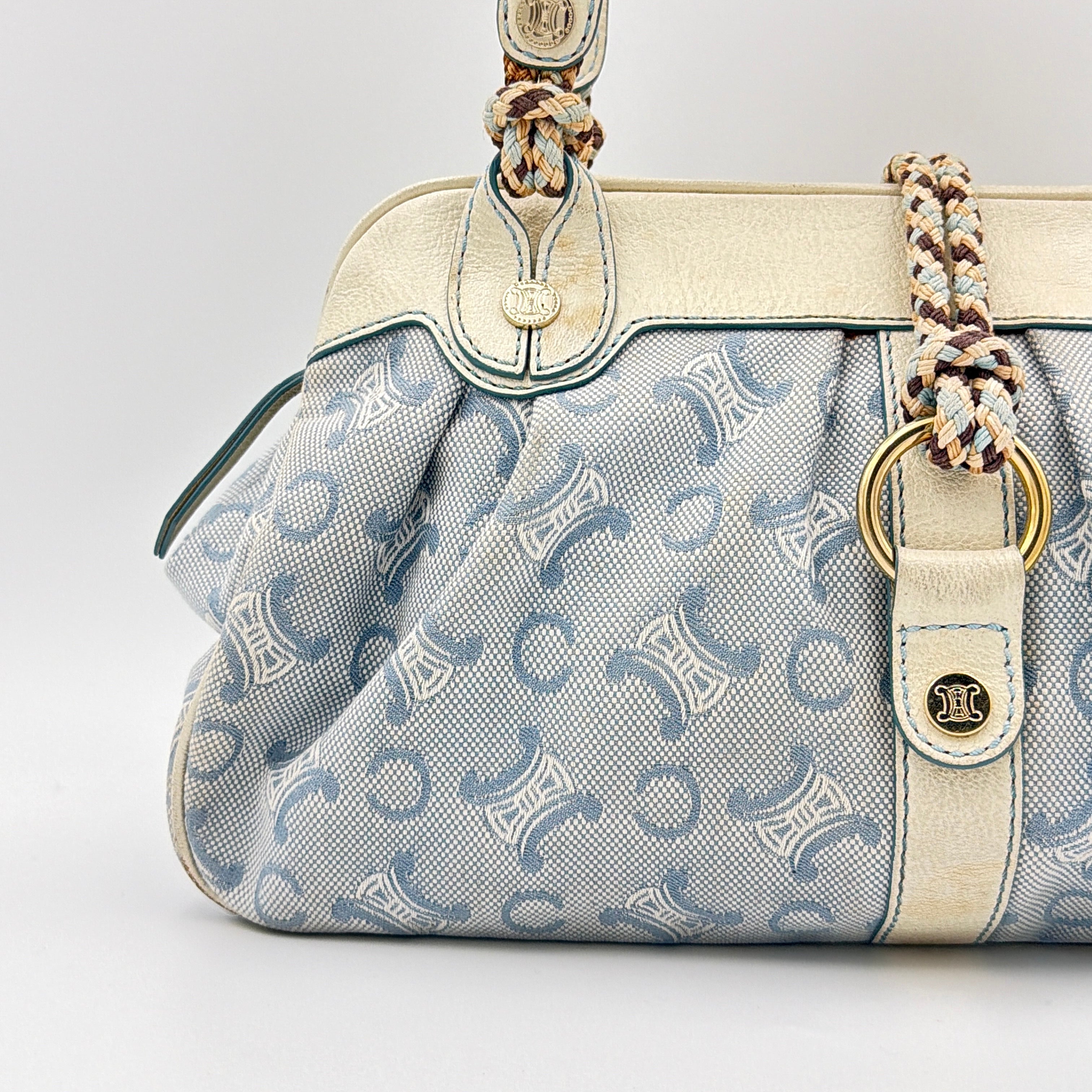 Front view of the Celine Macadam Canvas Shoulder Bag in blue canvas and cream leather with braided handles and gold hardware.