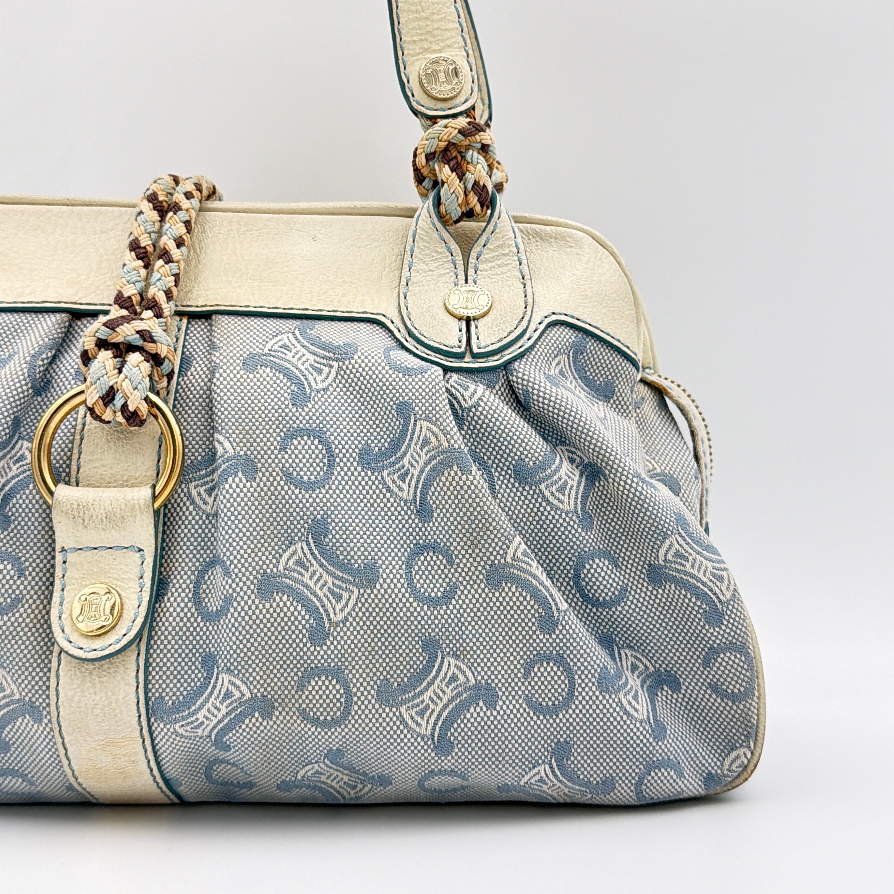 Front view of the Celine Macadam Canvas Shoulder Bag in blue canvas and cream leather with braided handles and gold hardware.