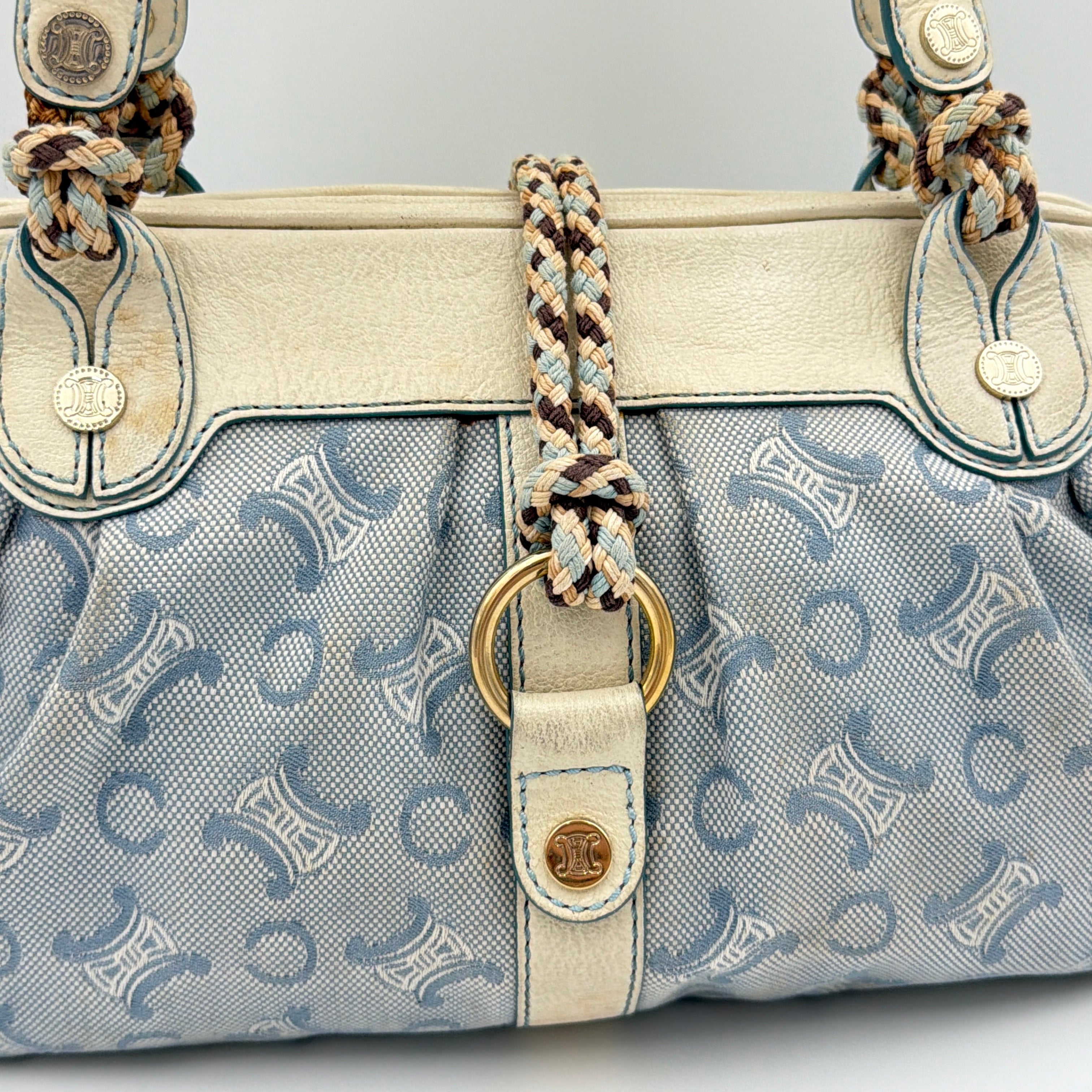 Front view of the Celine Macadam Canvas Shoulder Bag in blue canvas and cream leather with braided handles and gold hardware.