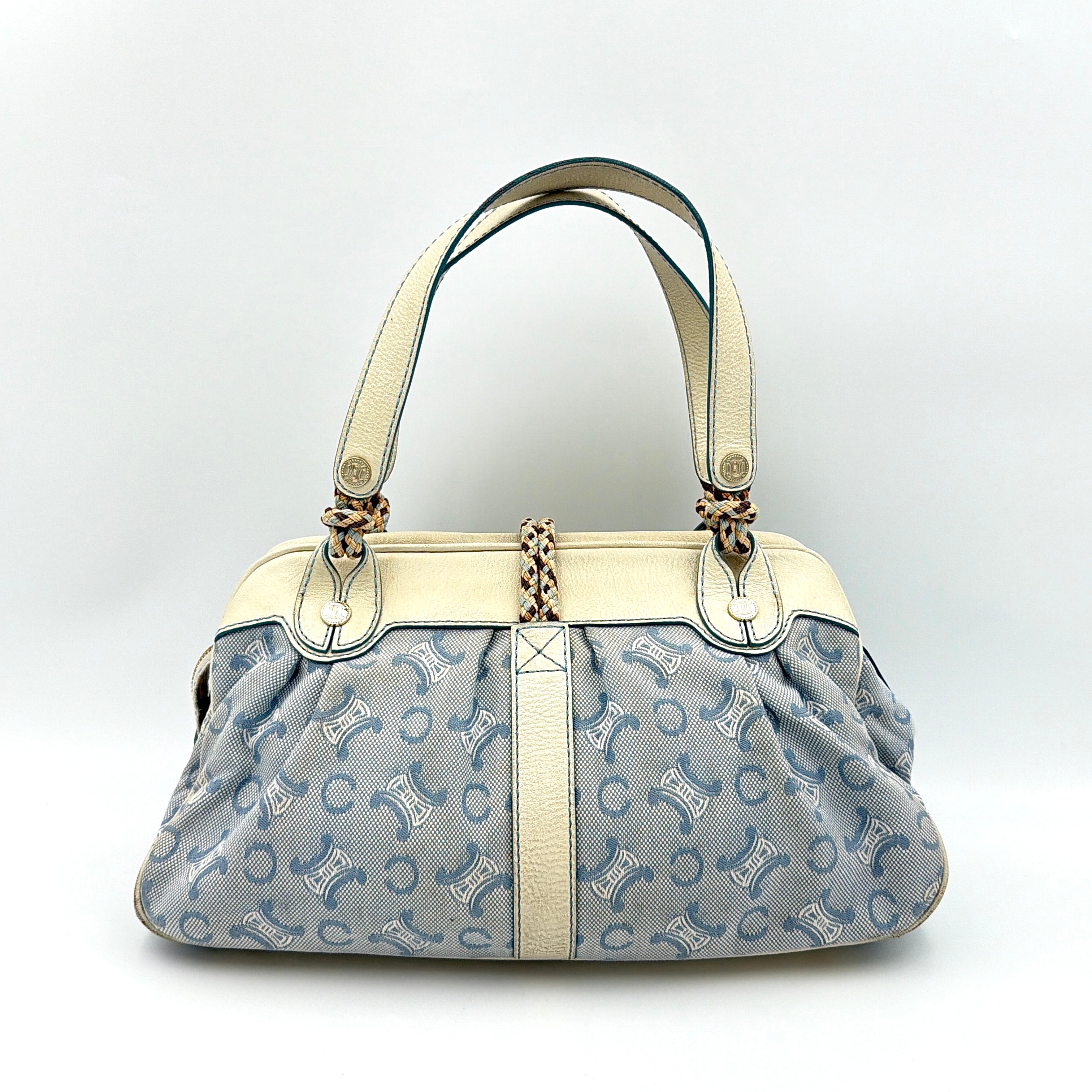Front view of the Celine Macadam Canvas Shoulder Bag in blue canvas and cream leather with braided handles and gold hardware.