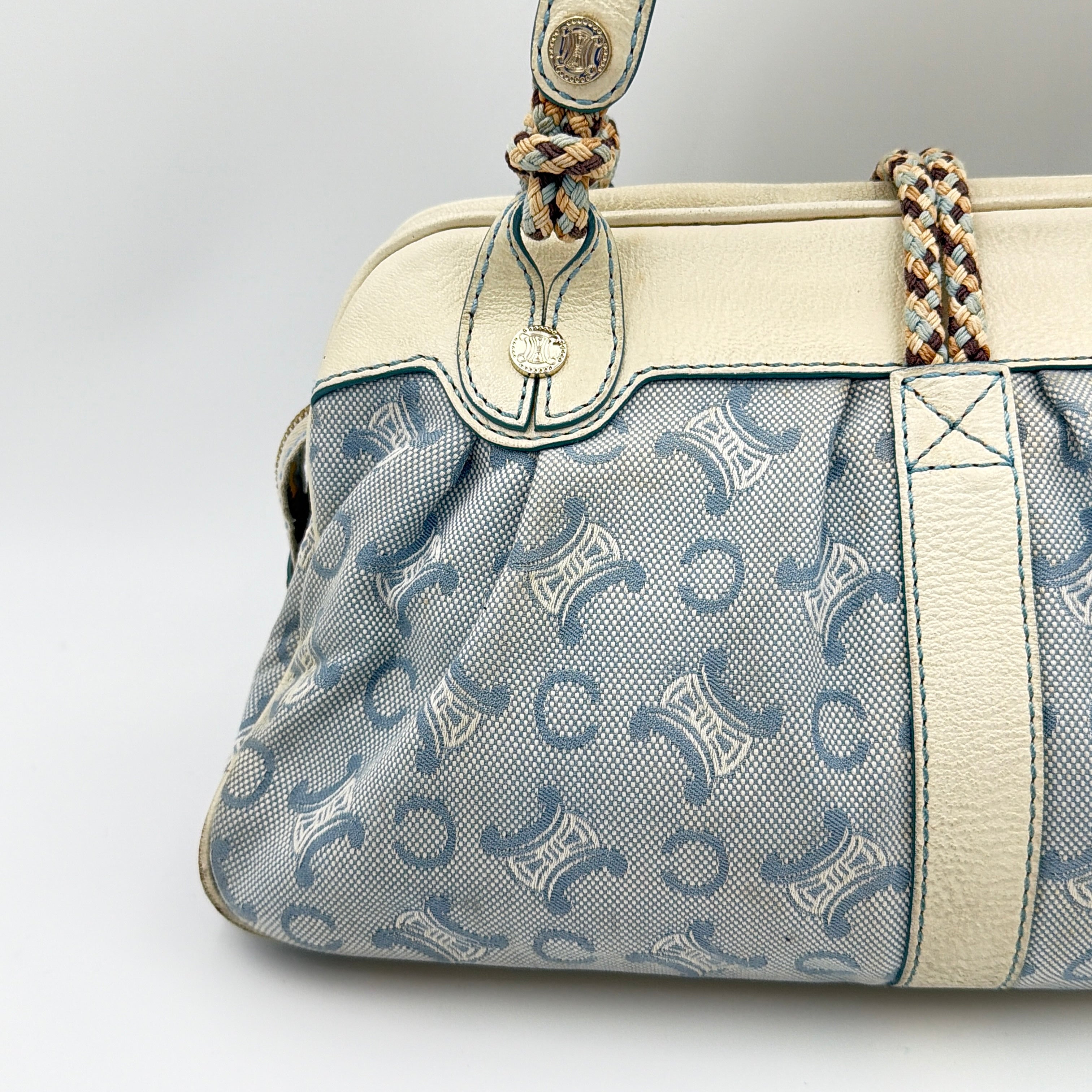 Front view of the Celine Macadam Canvas Shoulder Bag in blue canvas and cream leather with braided handles and gold hardware.