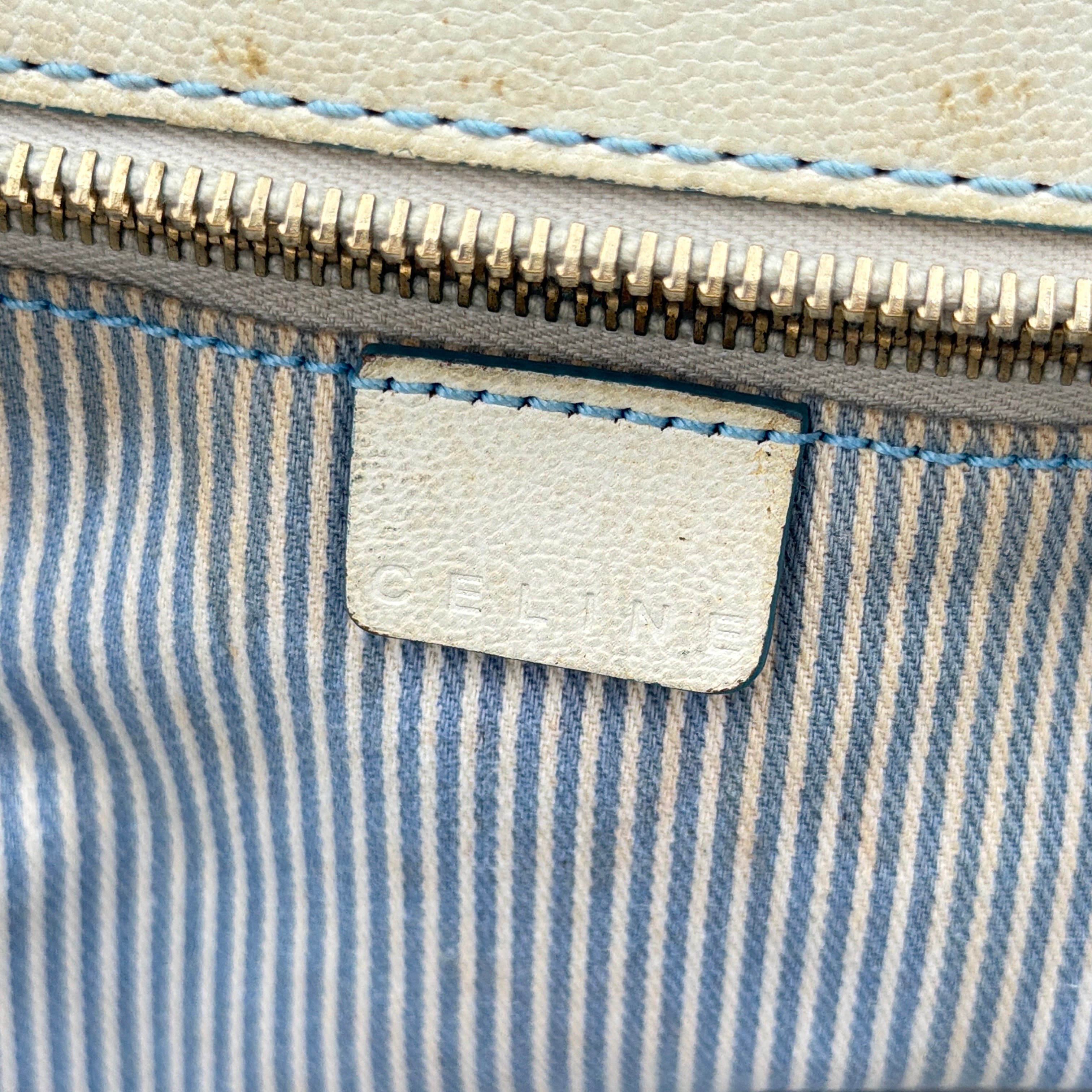 Front view of the Celine Macadam Canvas Shoulder Bag in blue canvas and cream leather with braided handles and gold hardware.