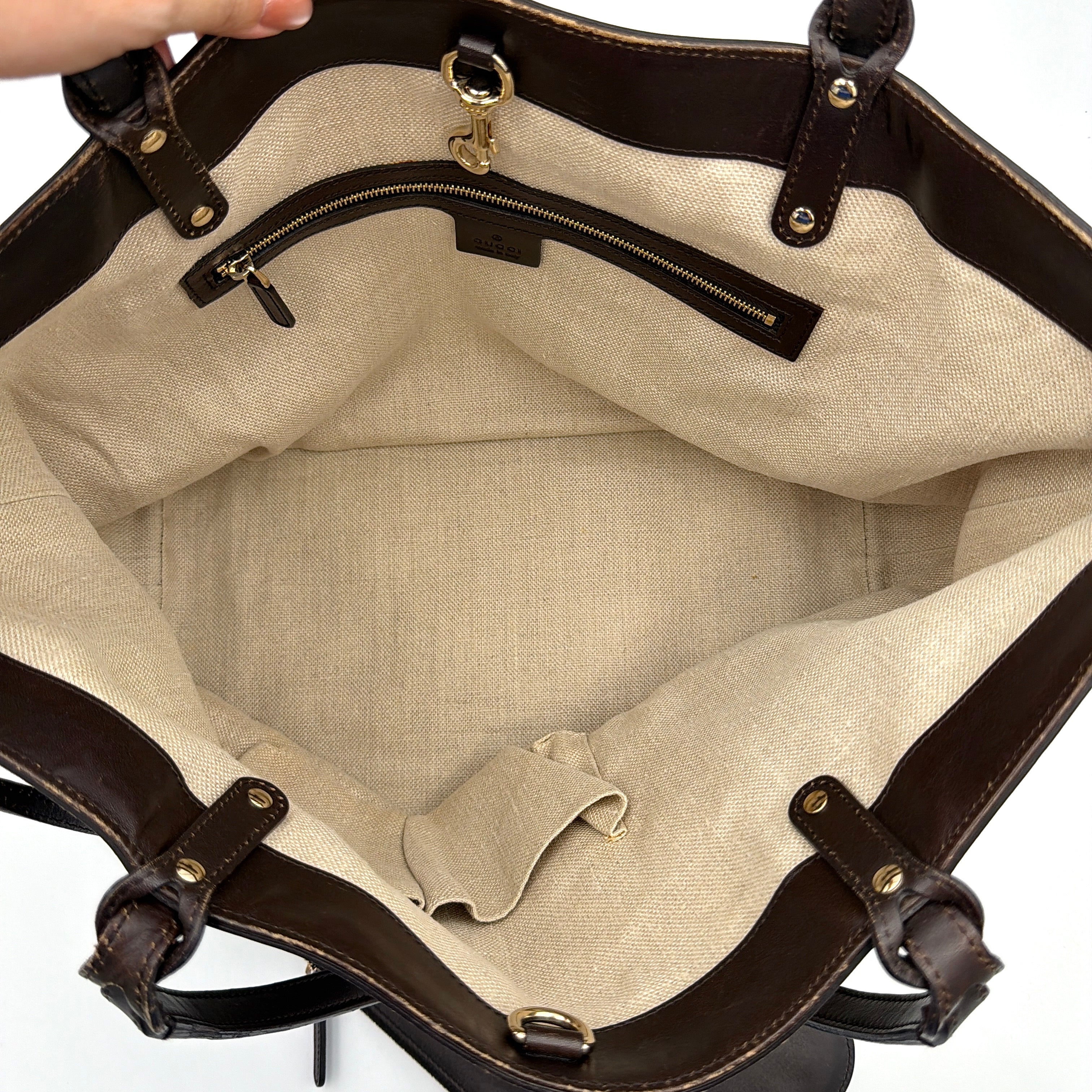 Gucci beige canvas shoulder bag with brown leather trim, bold Gucci logo, and matching detachable leather pouch.