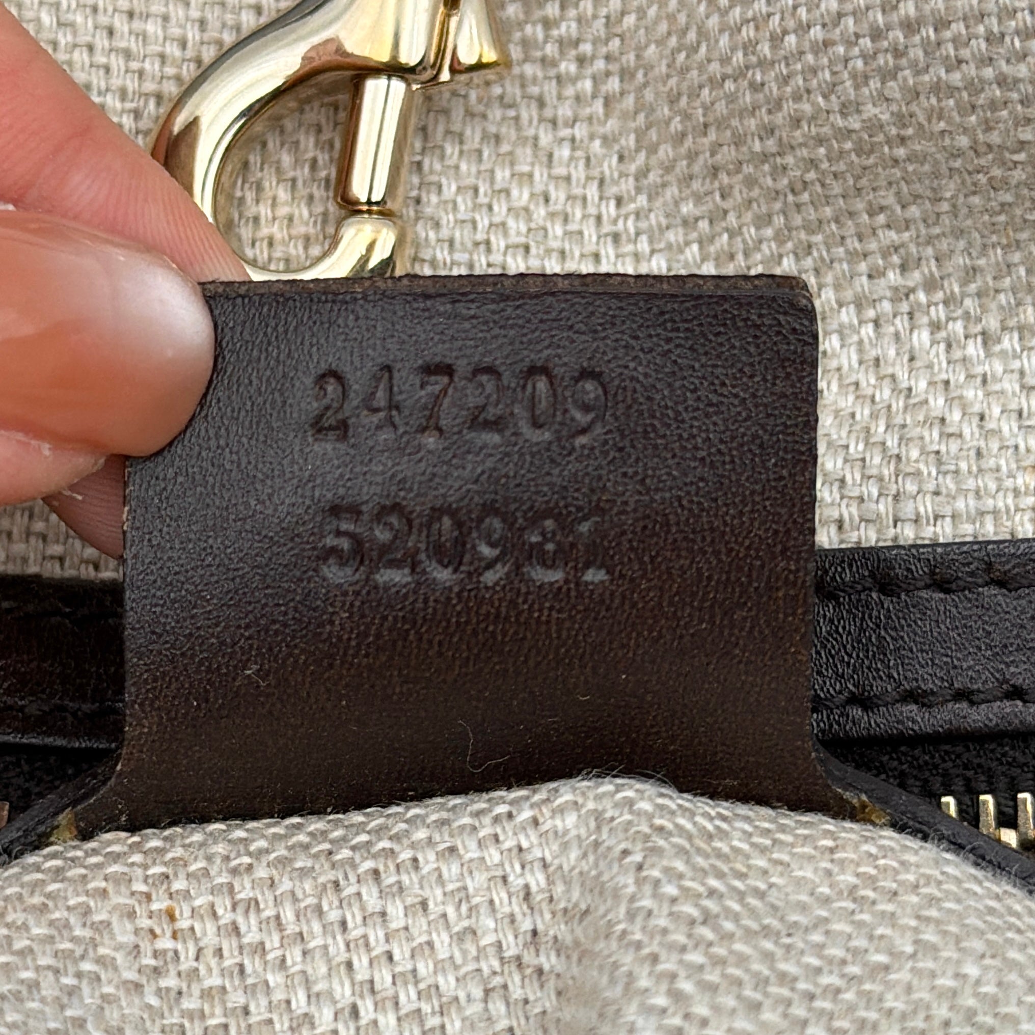 Gucci beige canvas shoulder bag with brown leather trim, bold Gucci logo, and matching detachable leather pouch.