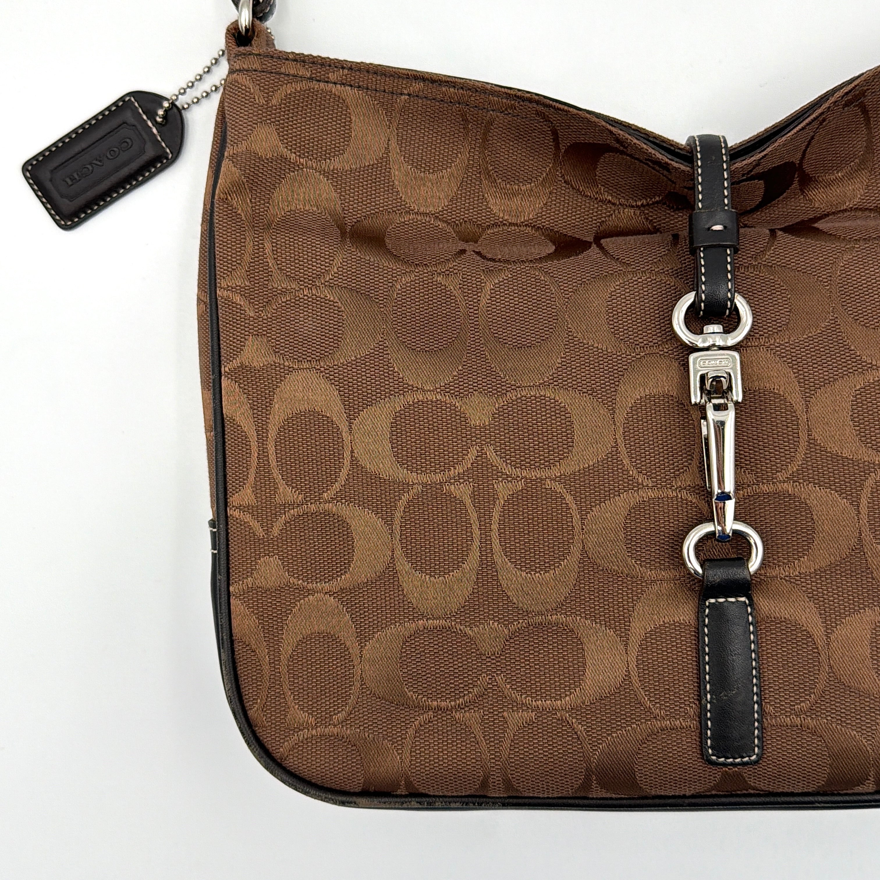 Coach Hobo Signature Clip canvas handbag in brown with black leather trim and silver hardware displayed against a plain background.
