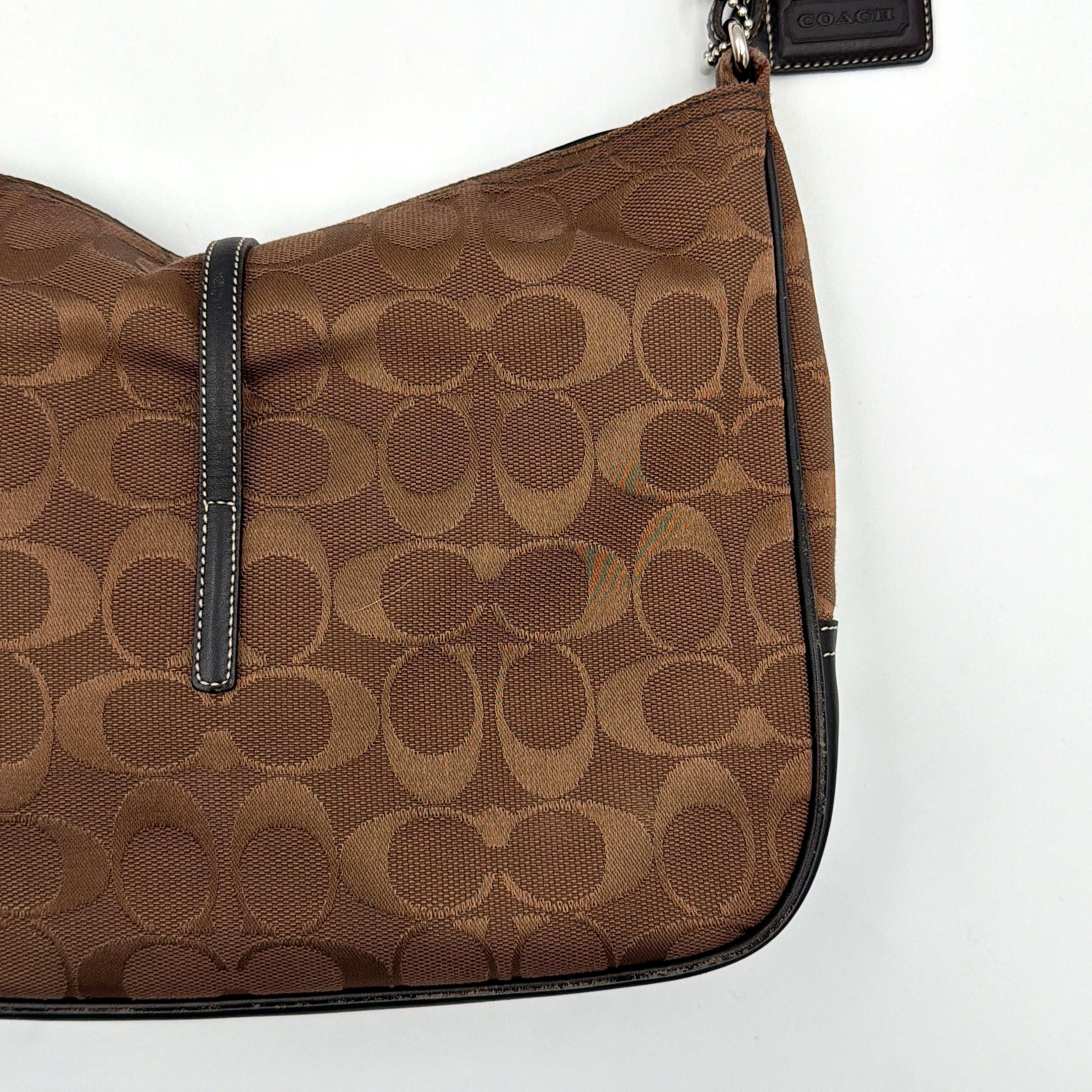 Coach Hobo Signature Clip canvas handbag in brown with black leather trim and silver hardware displayed against a plain background.