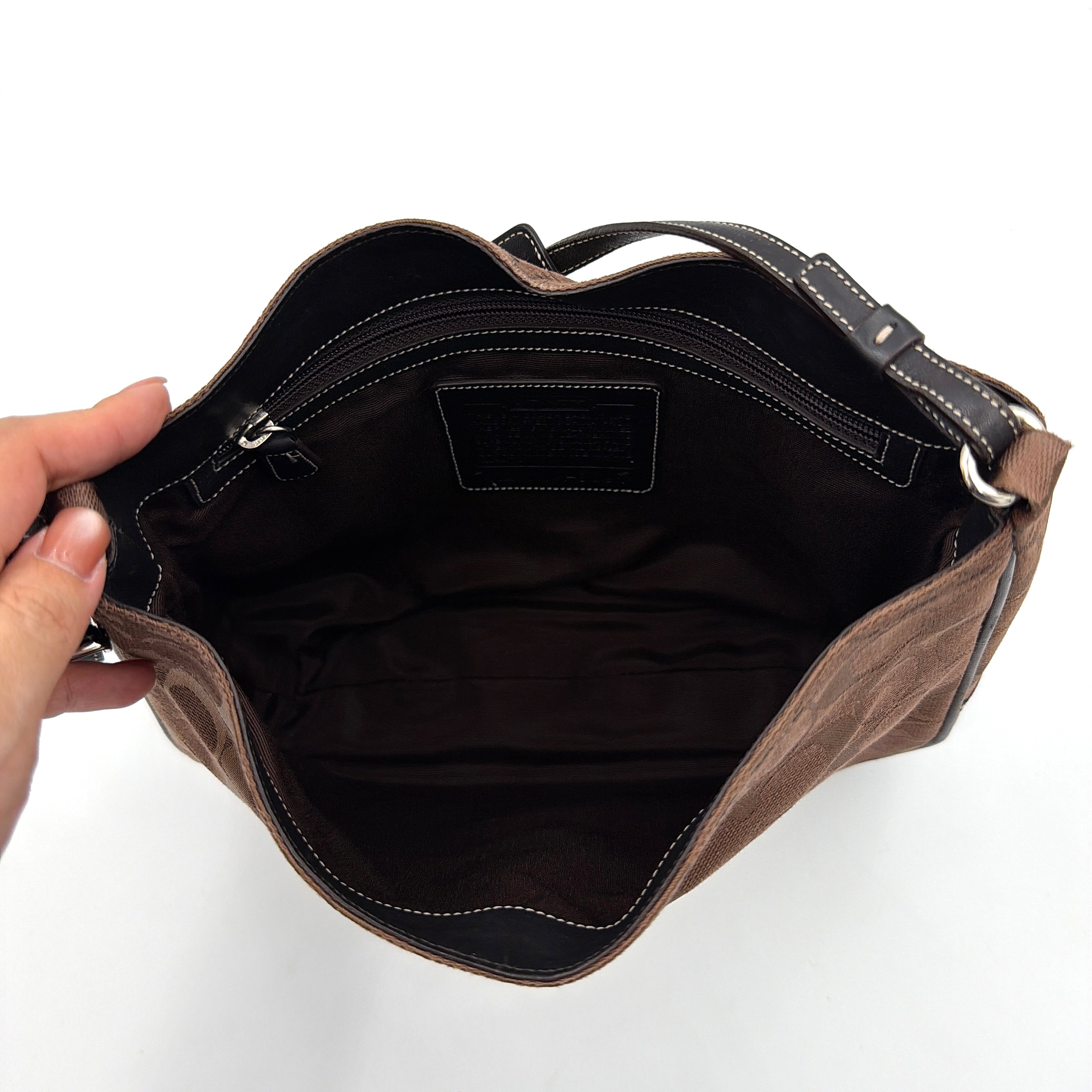 Coach Hobo Signature Clip canvas handbag in brown with black leather trim and silver hardware displayed against a plain background.