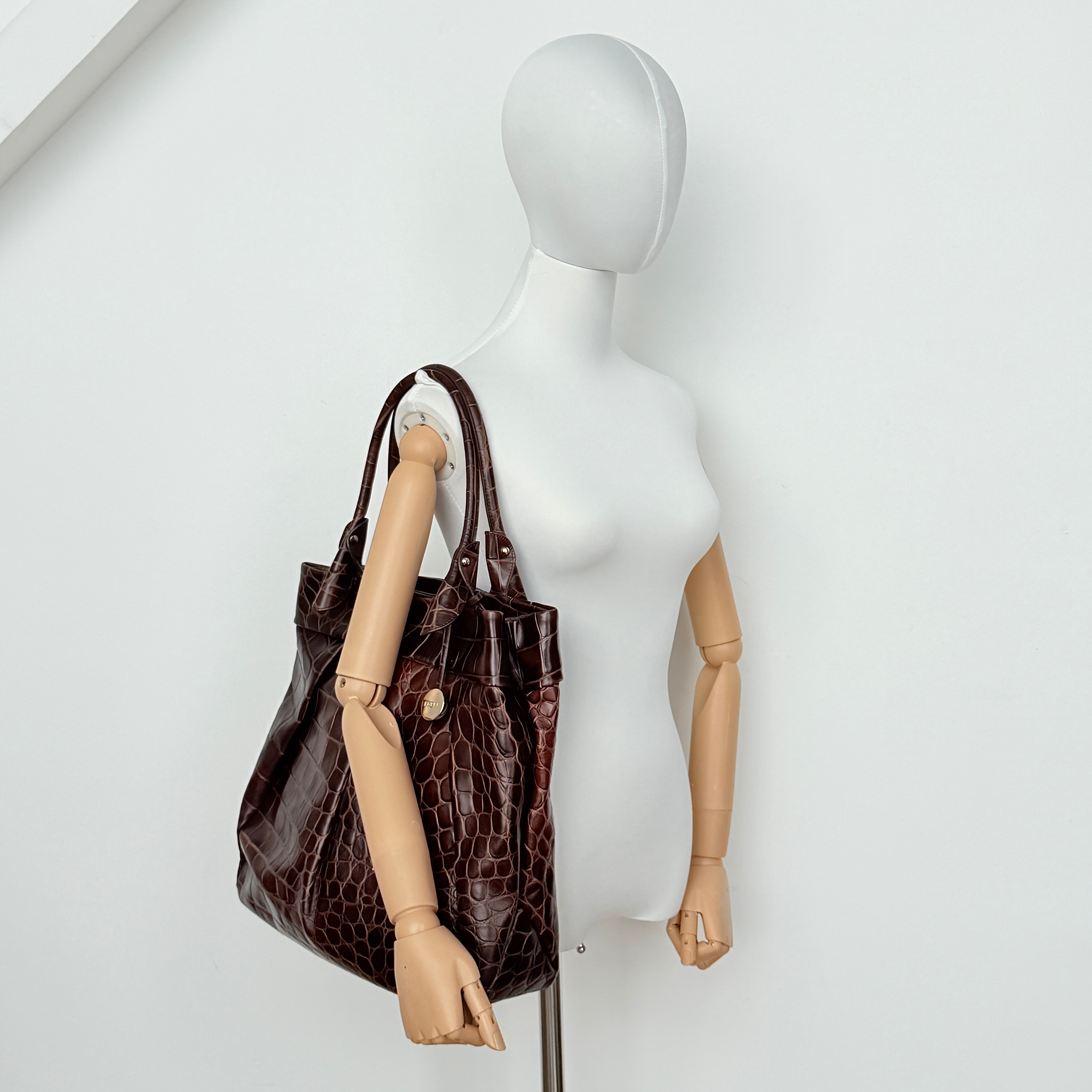 Furla dark brown croc-embossed leather tote bag with gold logo charm, structured silhouette, and double handles.
