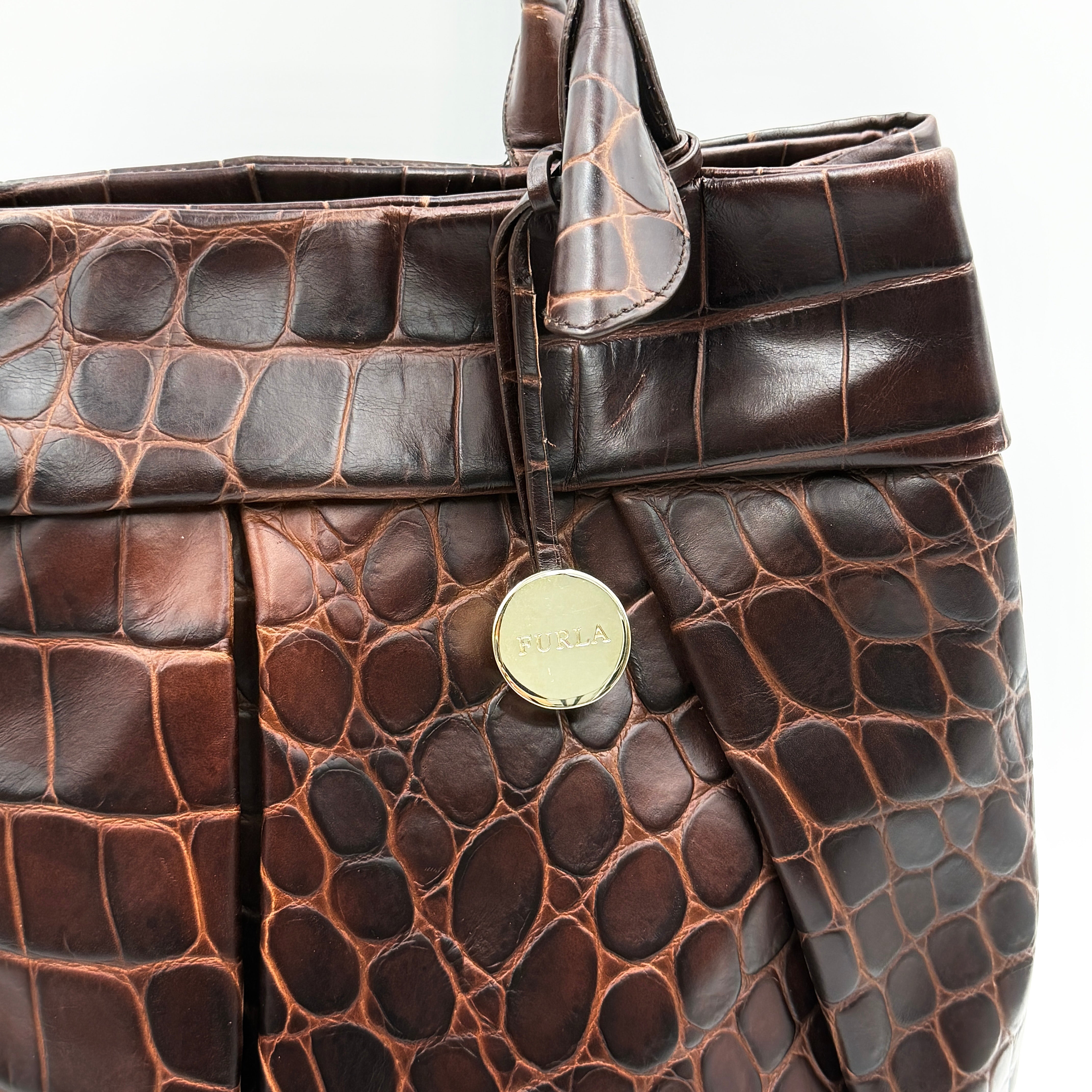 Furla dark brown croc-embossed leather tote bag with gold logo charm, structured silhouette, and double handles.