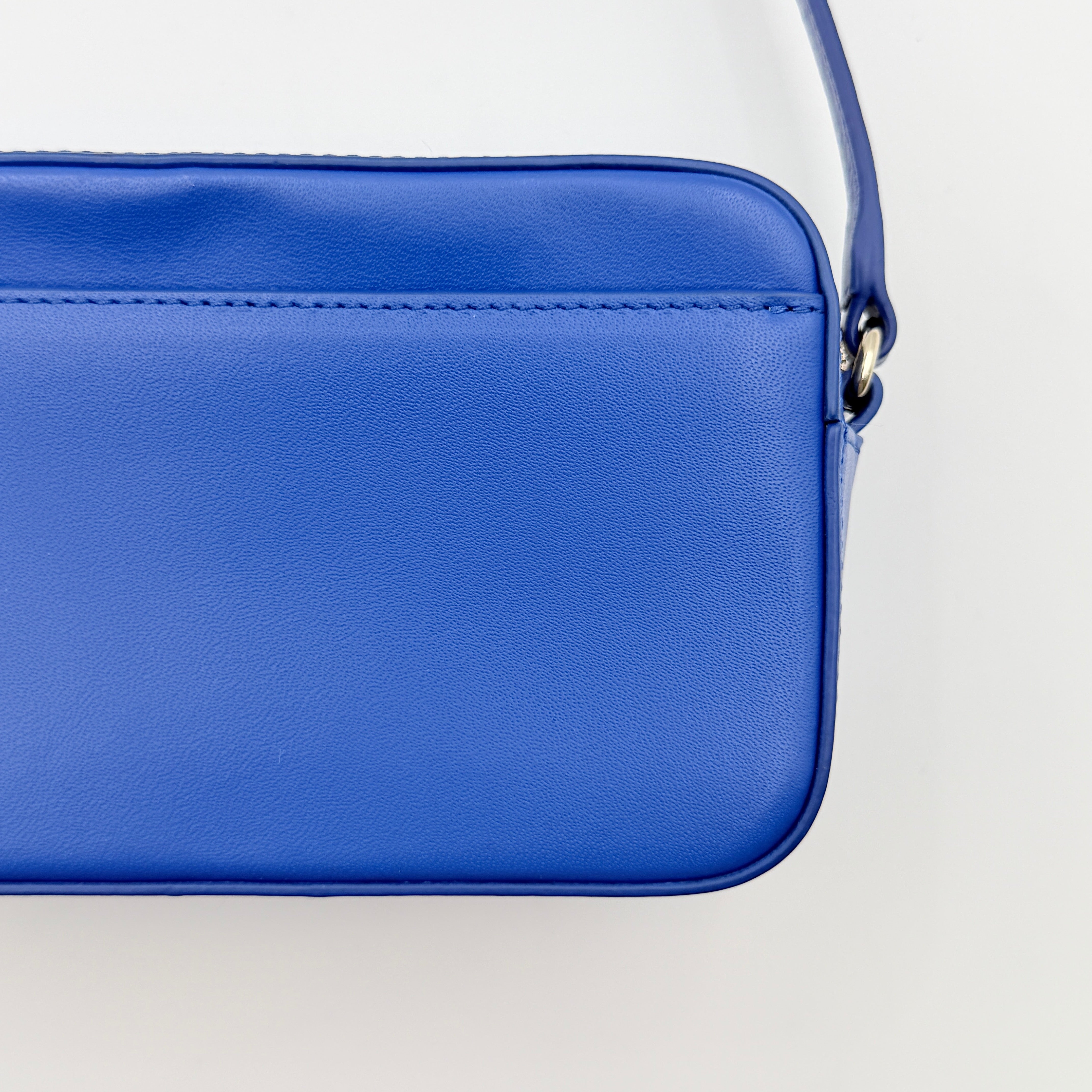 Furla Primula Mini Camera Crossbody Bag in vibrant blue leather with embossed logo, shown with adjustable strap.