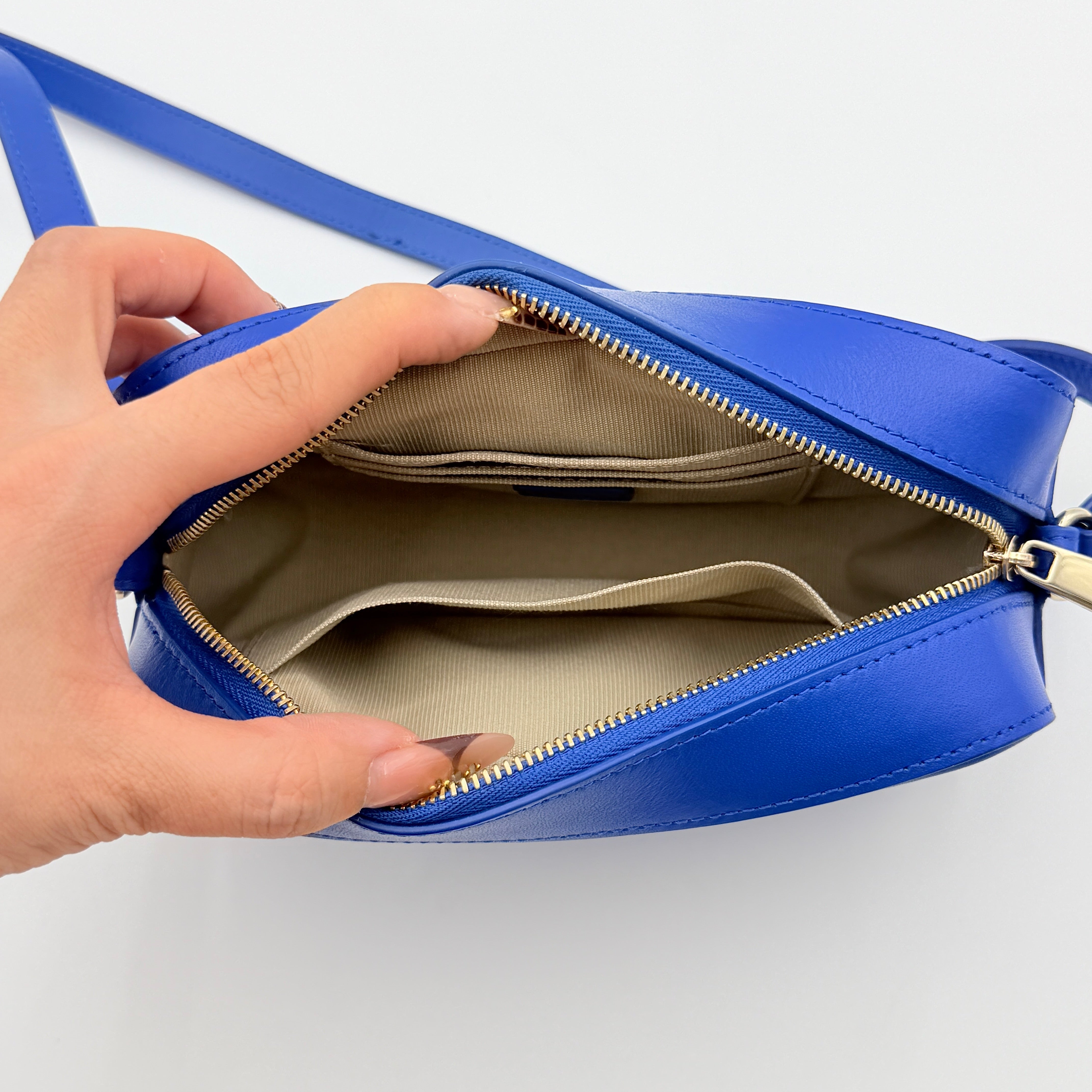 Furla Primula Mini Camera Crossbody Bag in vibrant blue leather with embossed logo, shown with adjustable strap.