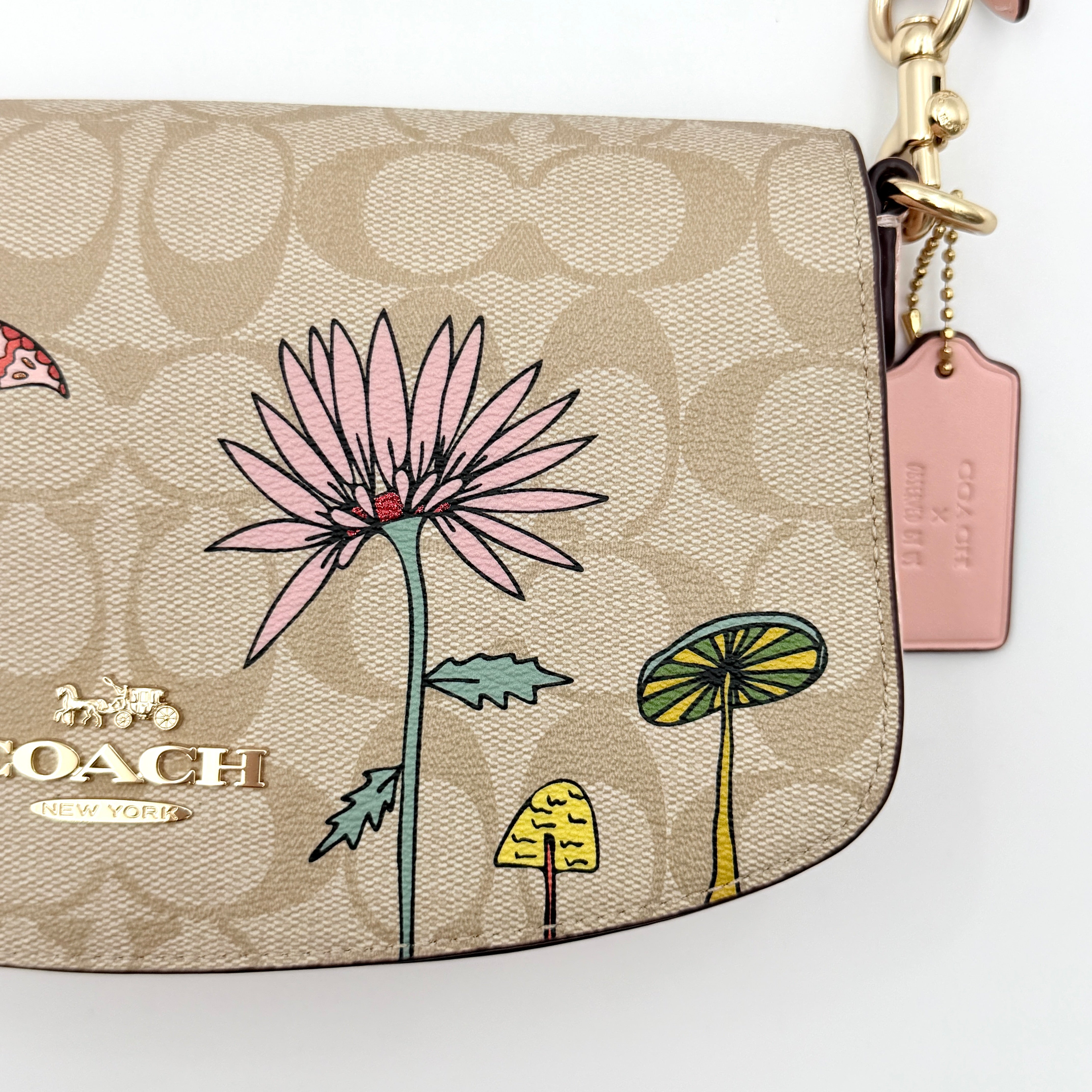 Coach X Observed By Us Andrea Shoulder Bag in beige monogram canvas with pink illustrations and pink leather strap.