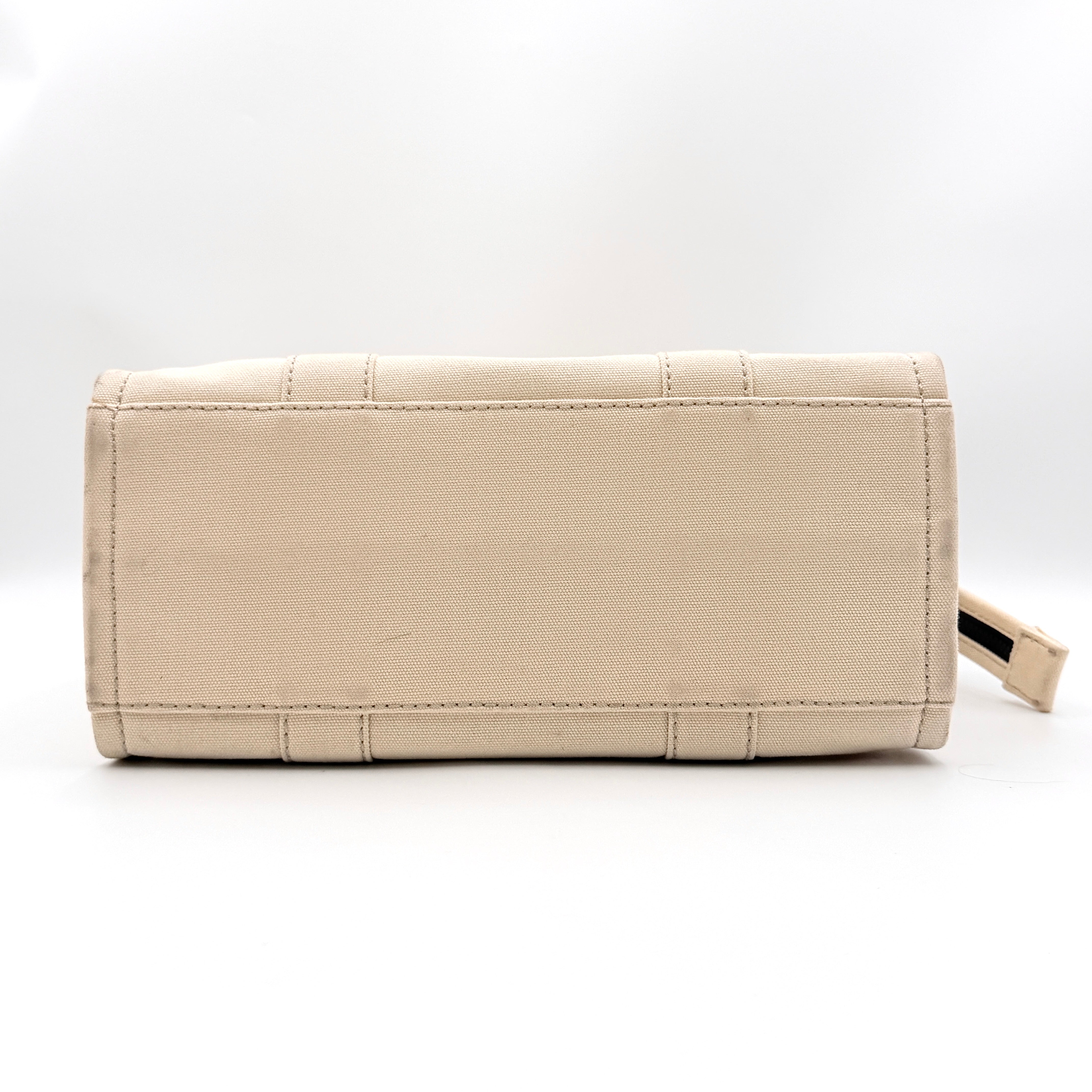 Marc Jacobs The Canvas Tote Bag in beige canvas with bold text, featuring top handles and zip closure.