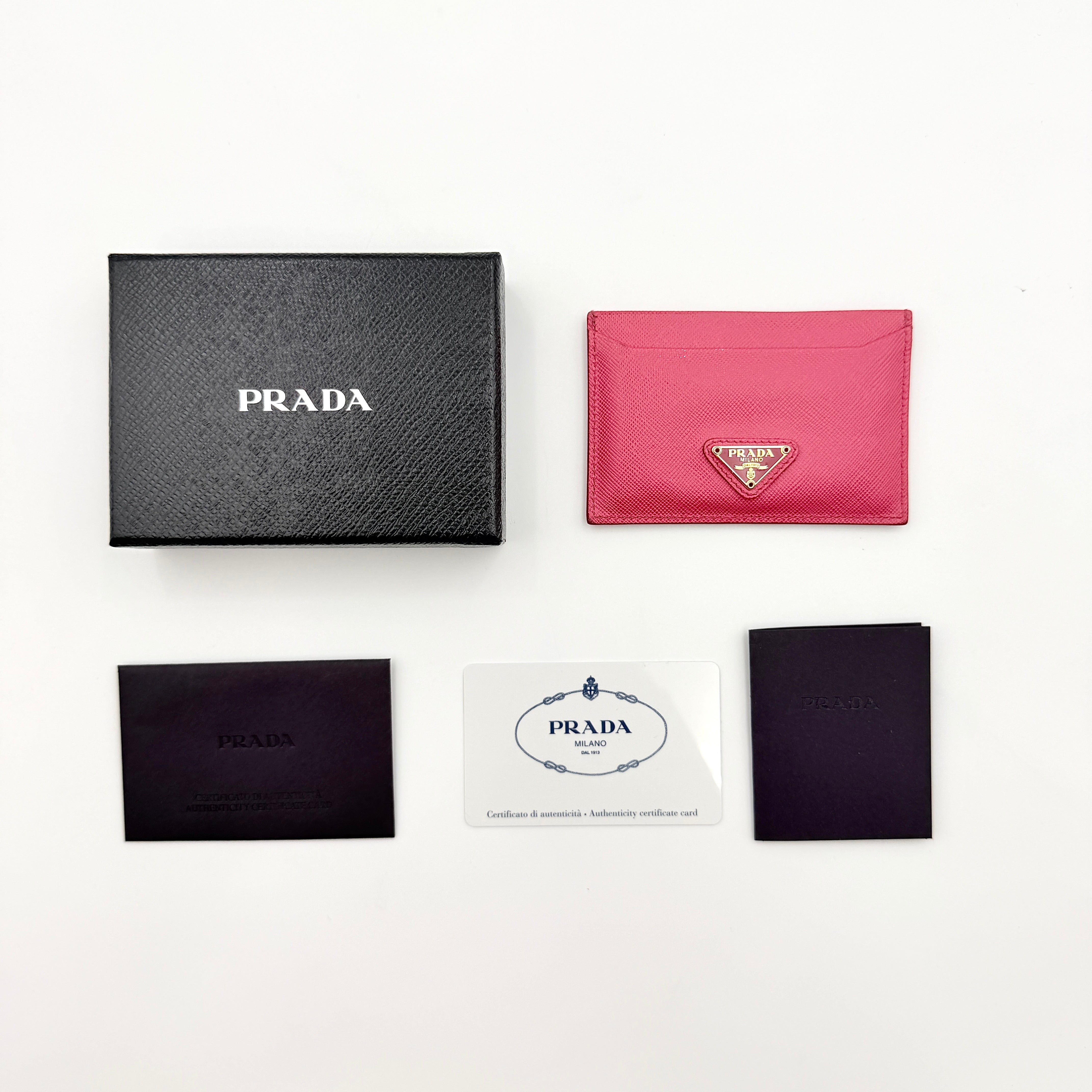 Prada Saffiano card holder in pink leather with gold-tone triangle logo plaque on the front.