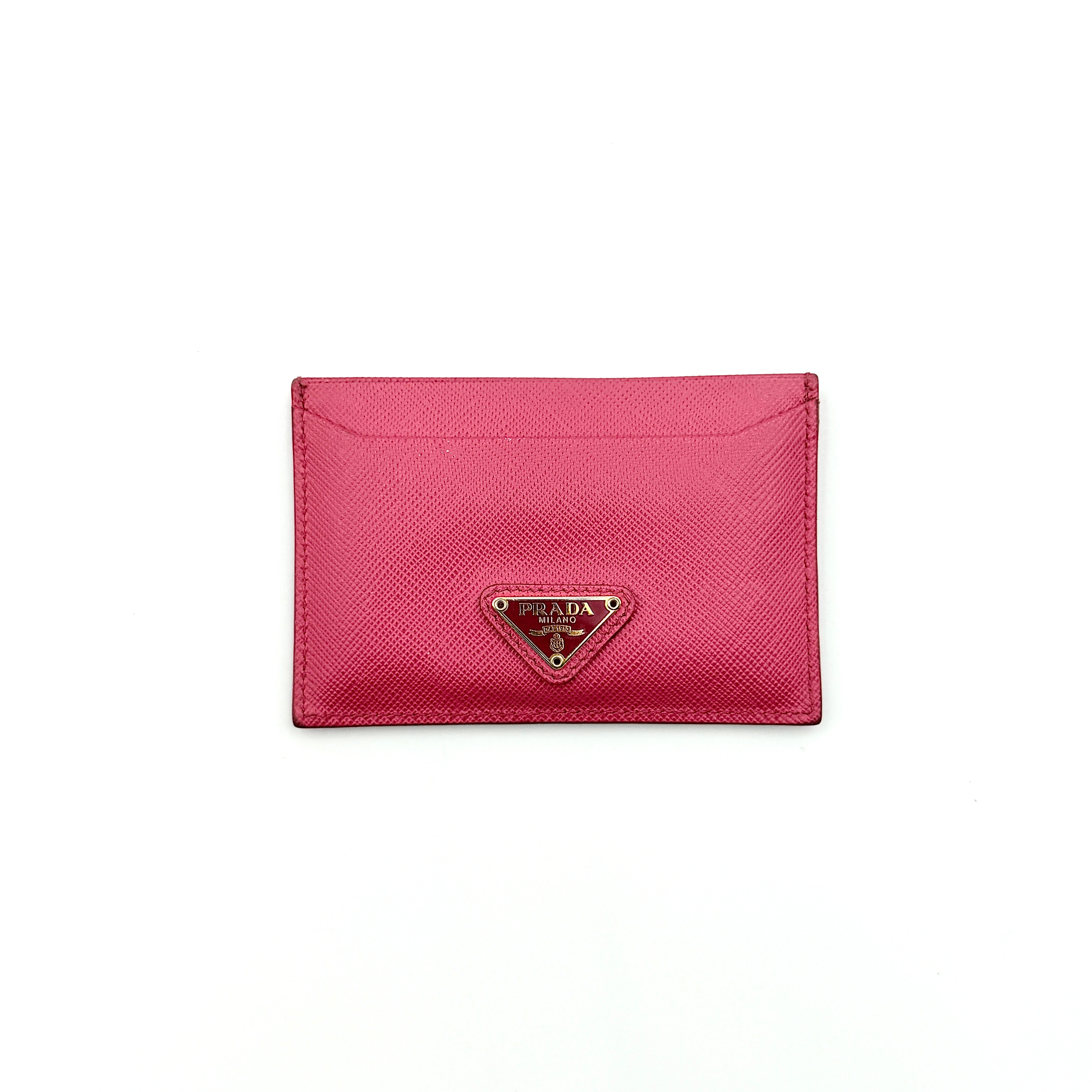 Prada Saffiano card holder in pink leather with gold-tone triangle logo plaque on the front.