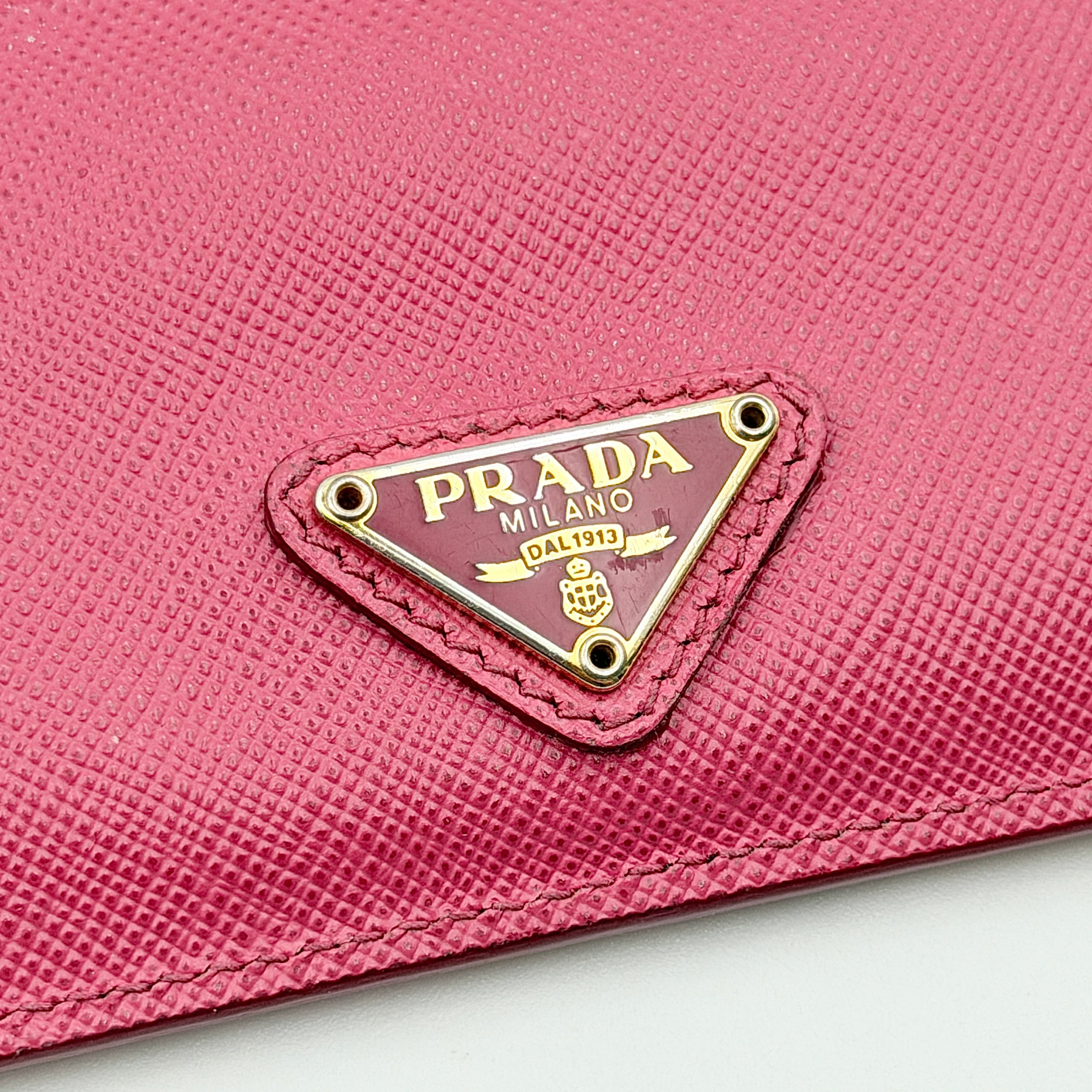 Prada Saffiano card holder in pink leather with gold-tone triangle logo plaque on the front.