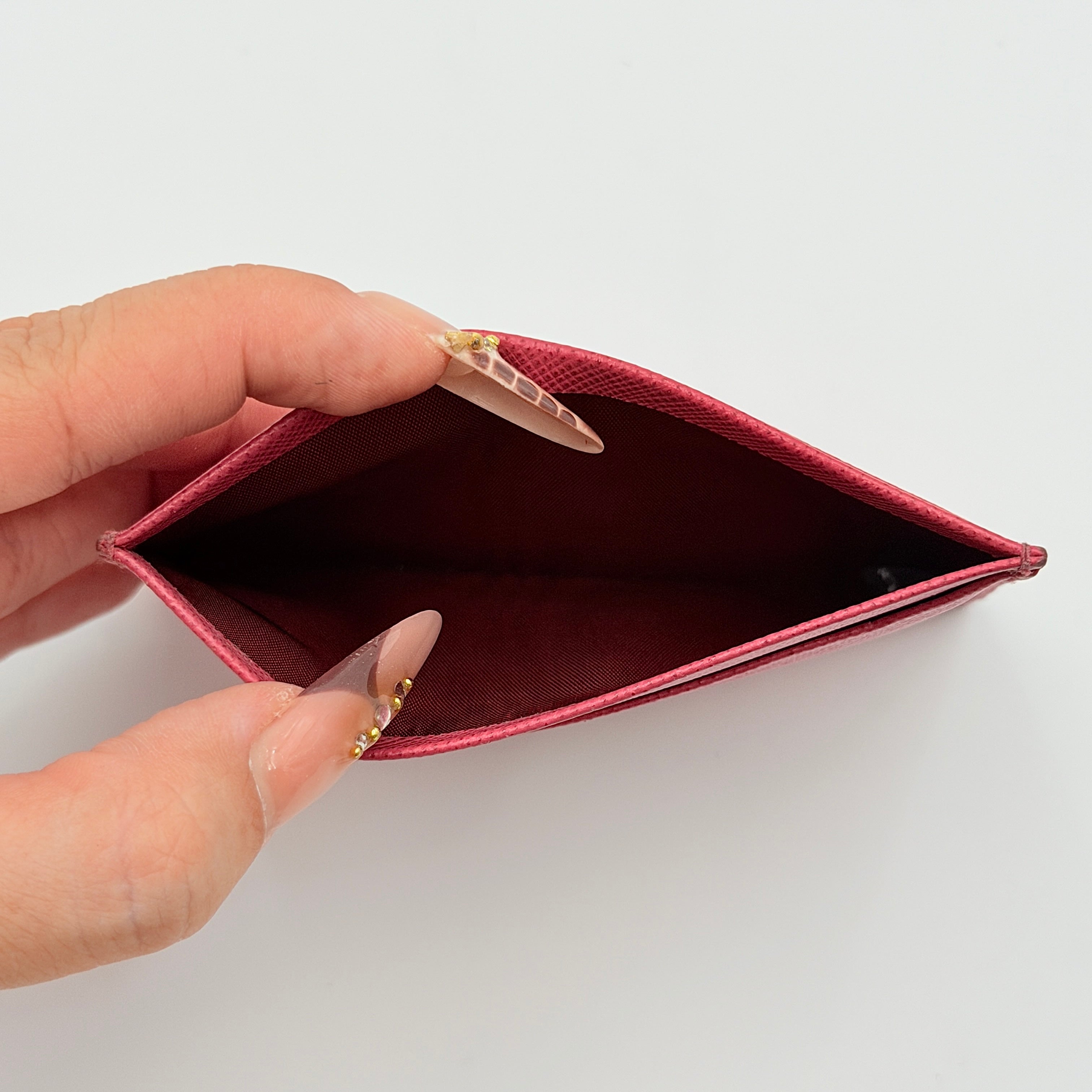 Prada Saffiano card holder in pink leather with gold-tone triangle logo plaque on the front.