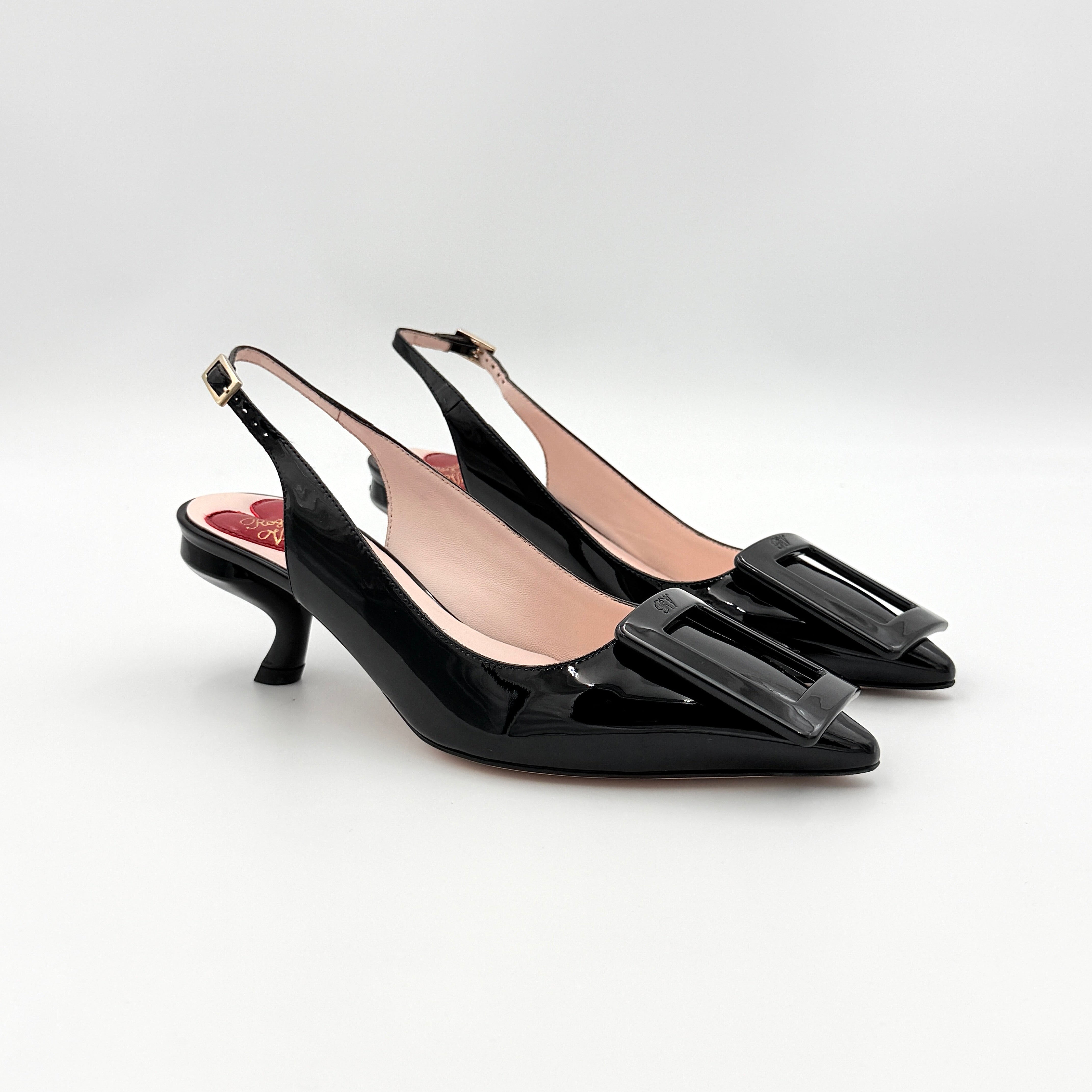 A pair of Roger Vivier Virgule black patent slingback pumps featuring a sculpted heel and oversized buckle at the toe.