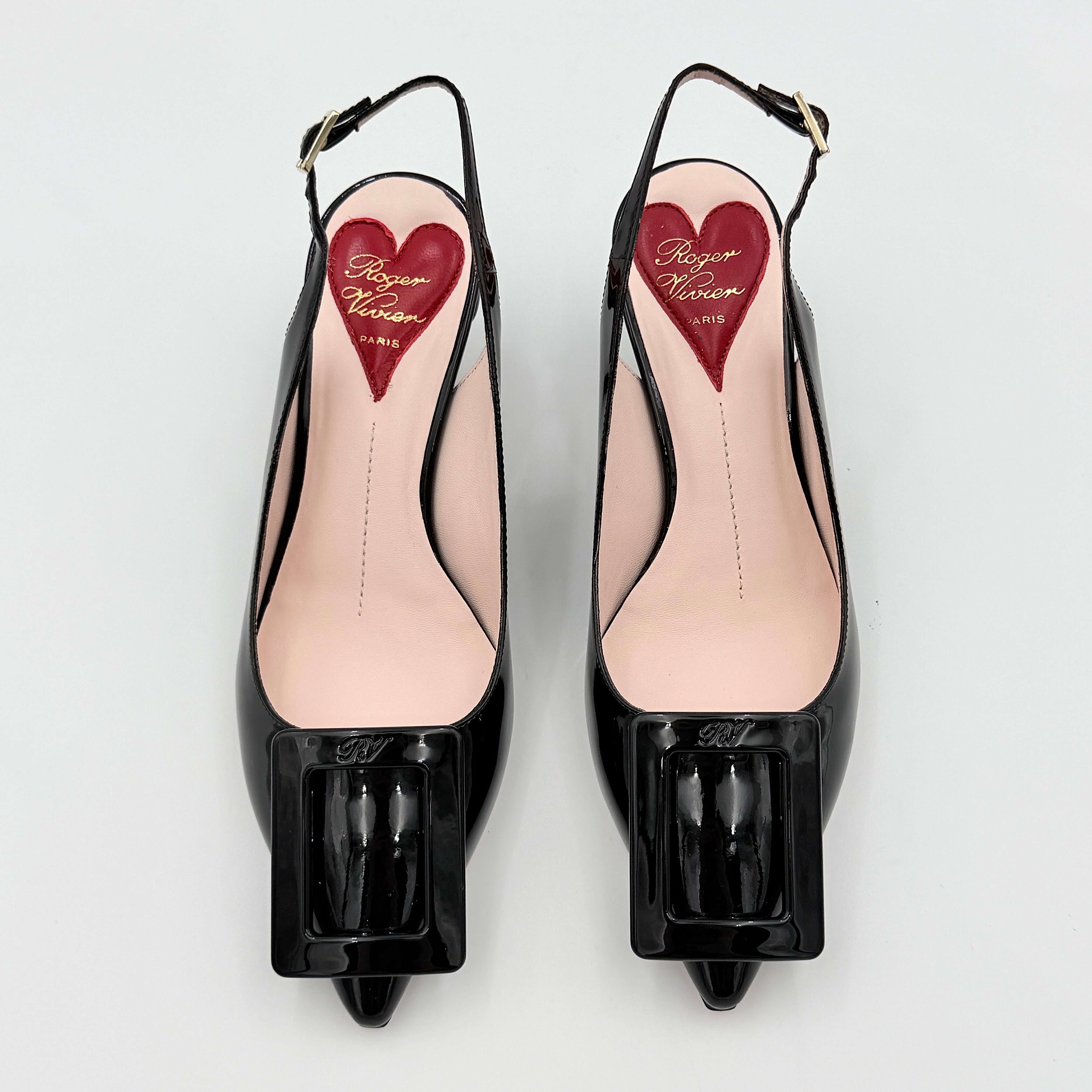 A pair of Roger Vivier Virgule black patent slingback pumps featuring a sculpted heel and oversized buckle at the toe.