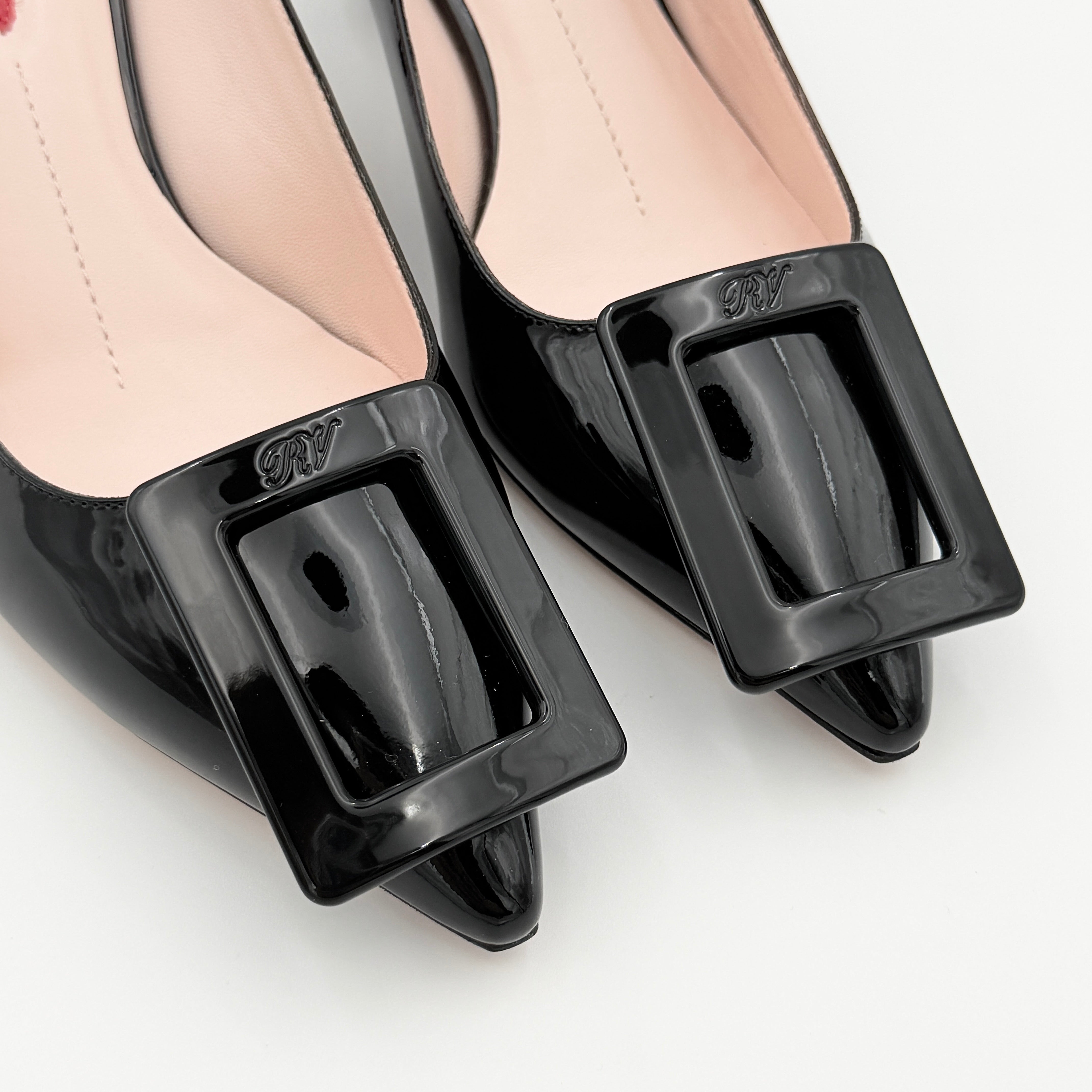 A pair of Roger Vivier Virgule black patent slingback pumps featuring a sculpted heel and oversized buckle at the toe.