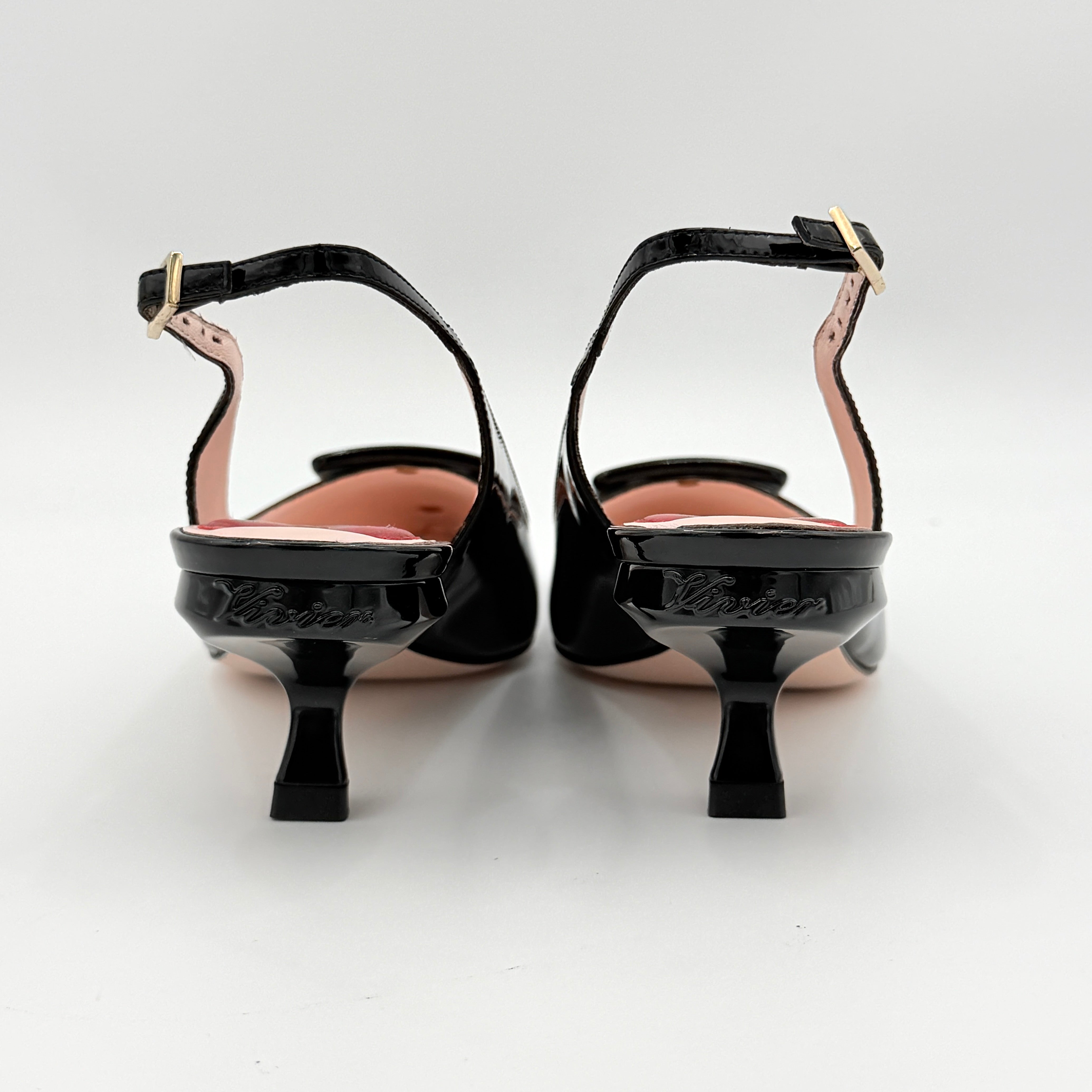A pair of Roger Vivier Virgule black patent slingback pumps featuring a sculpted heel and oversized buckle at the toe.