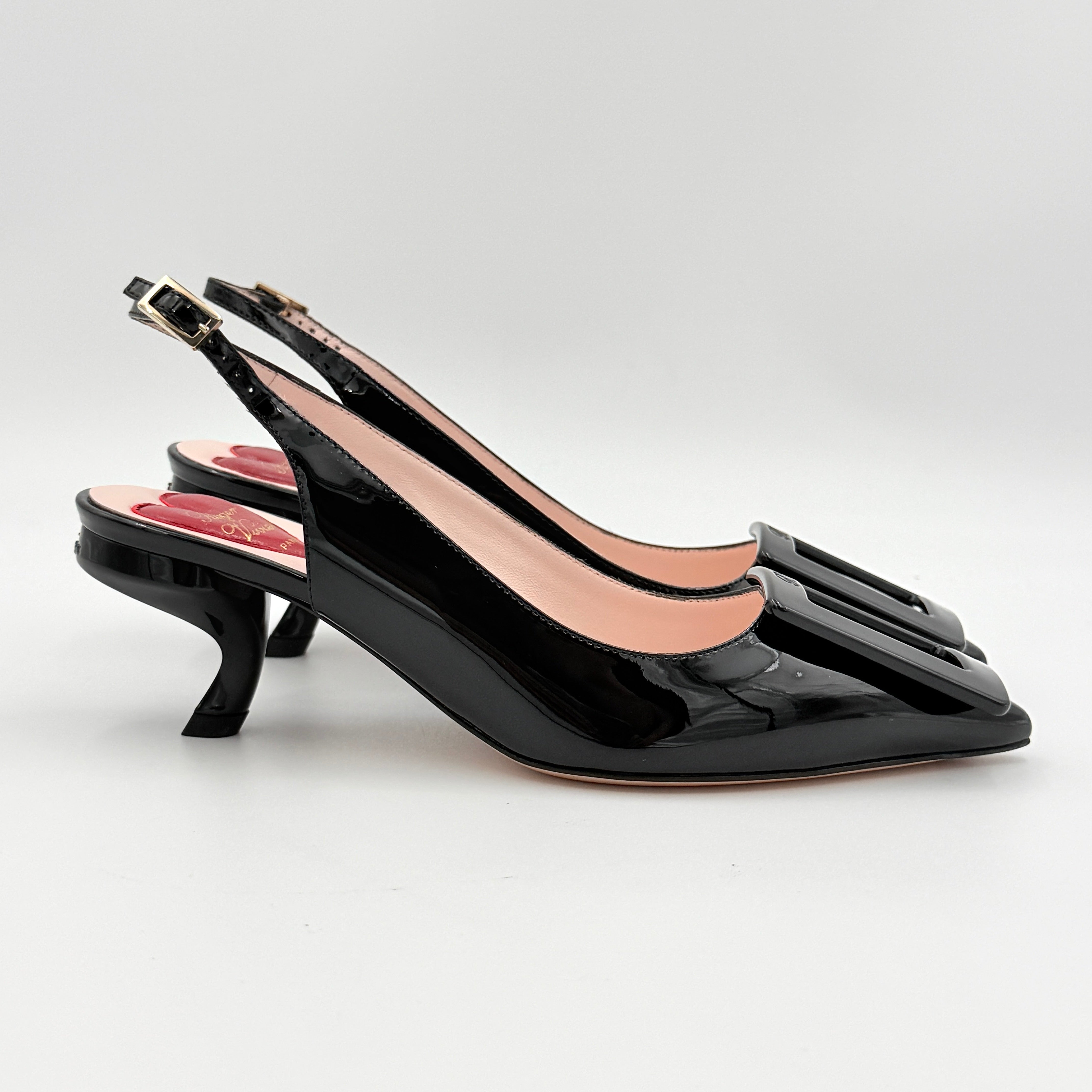 A pair of Roger Vivier Virgule black patent slingback pumps featuring a sculpted heel and oversized buckle at the toe.