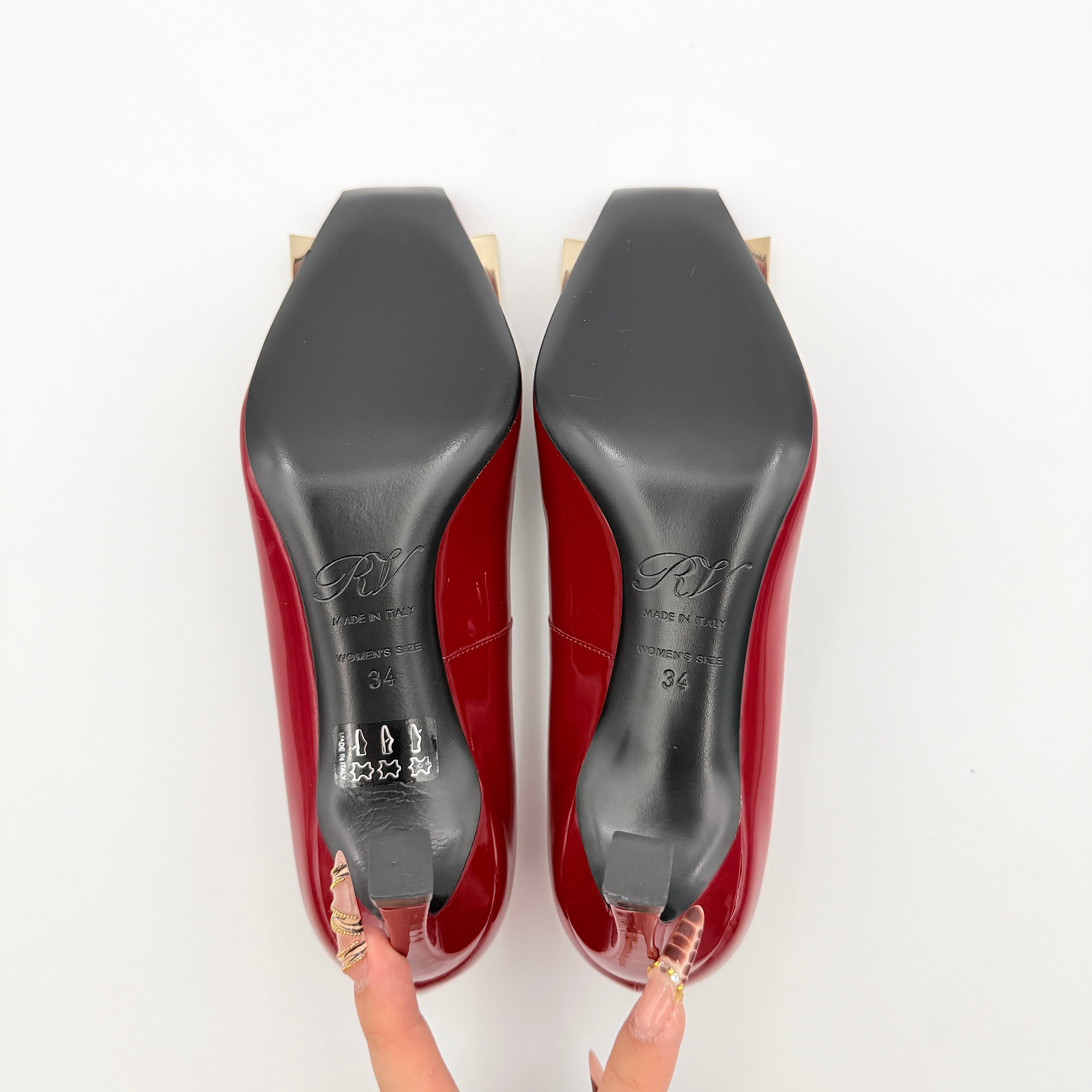 Pair of Roger Vivier Belle Vivier Trompette patent pumps in glossy red with gold-tone buckles, exuding a polished finish.