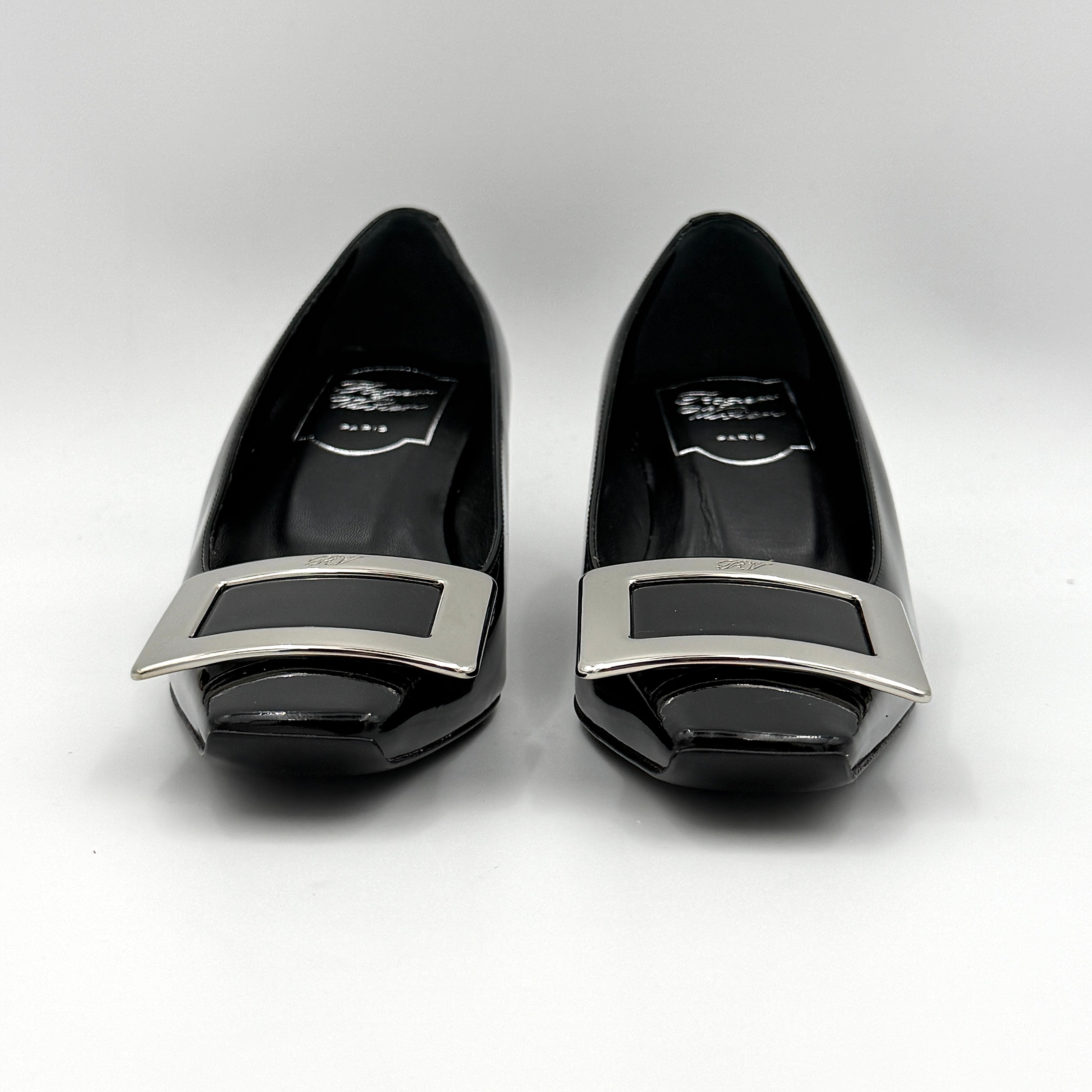 A pair of Roger Vivier Belle Vivier black patent pumps with signature silver-tone buckles, displayed at an angle.
