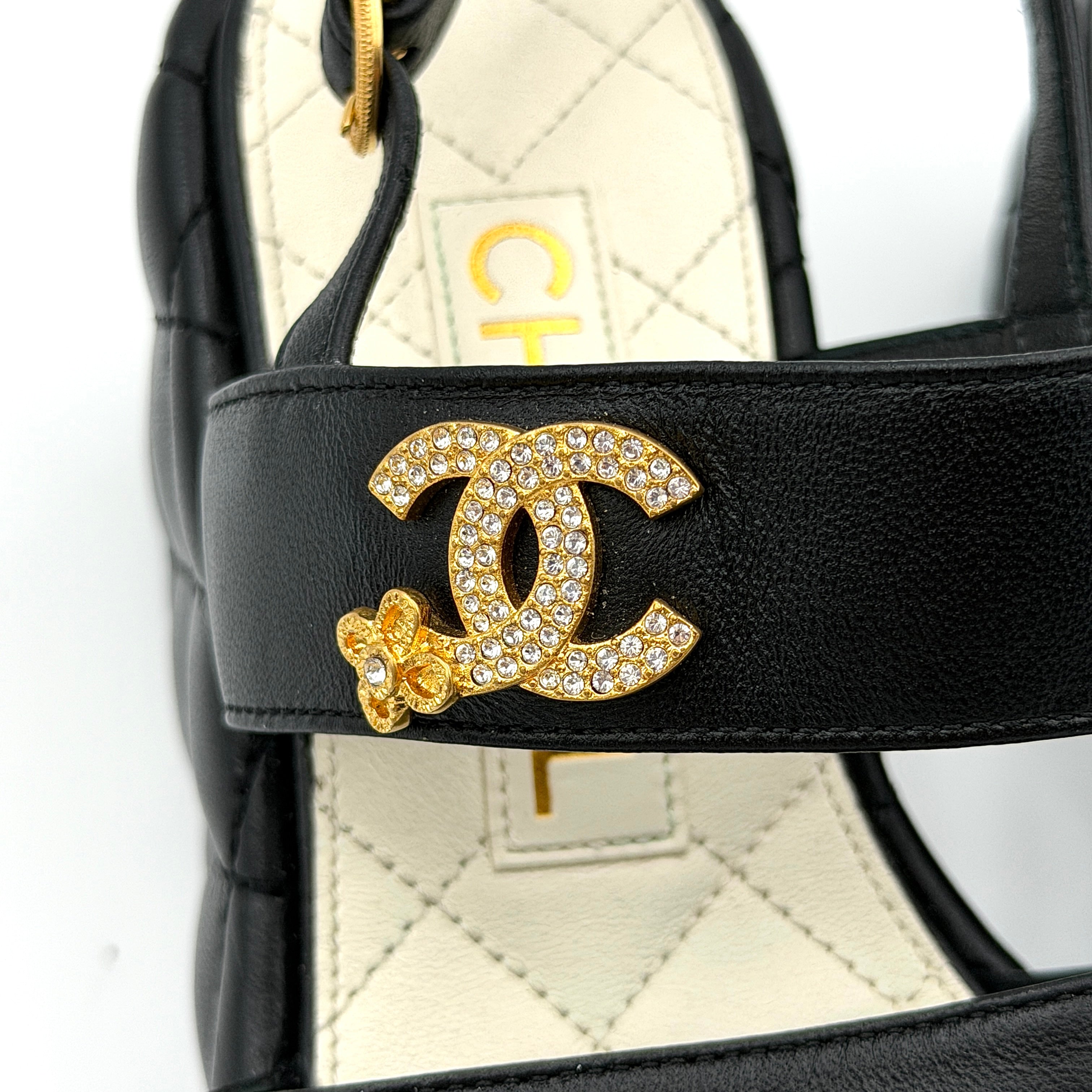 Chanel black quilted leather wedge platform sandals with gold crystal CC hardware and ankle strap detailing.
