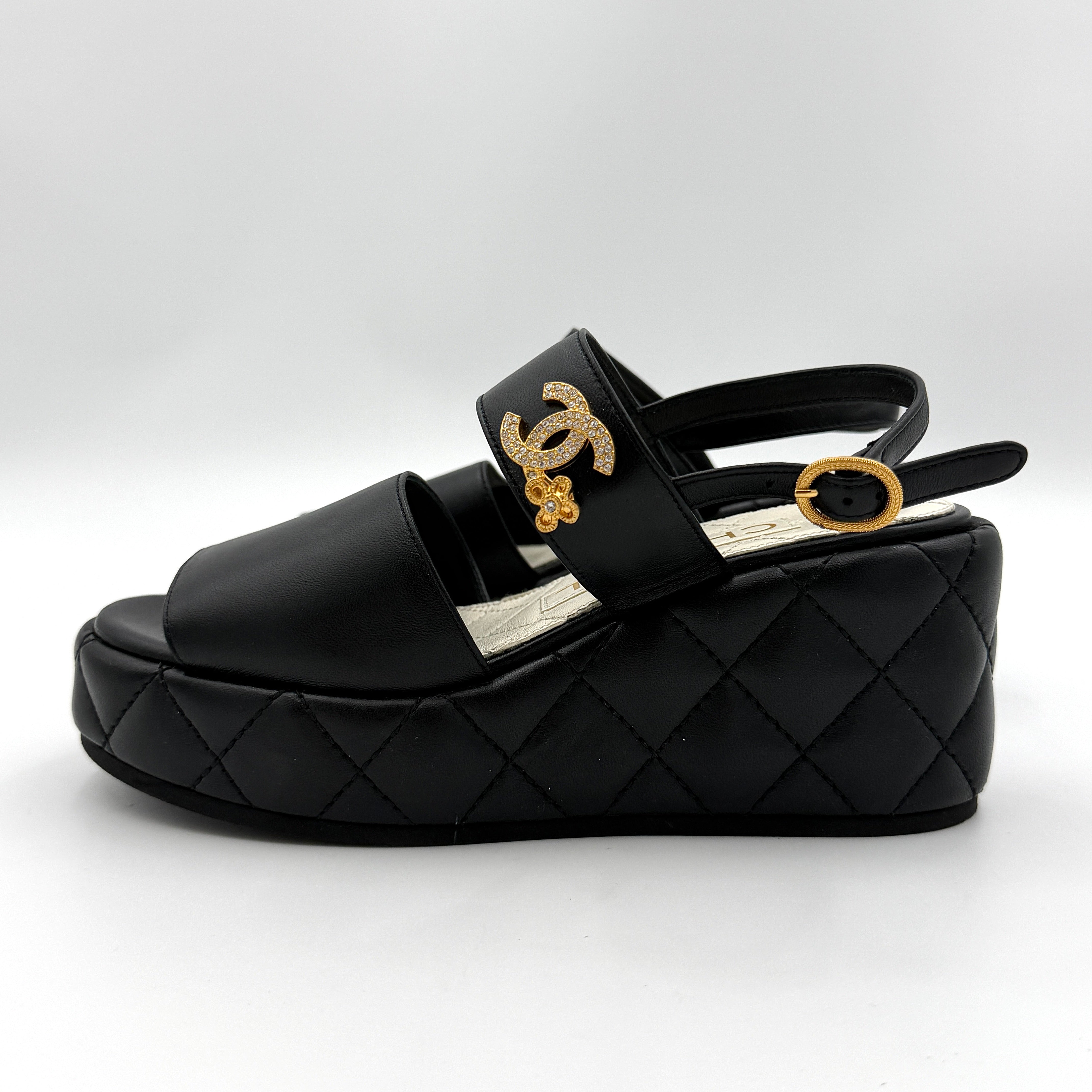 Chanel black quilted leather wedge platform sandals with gold crystal CC hardware and ankle strap detailing.