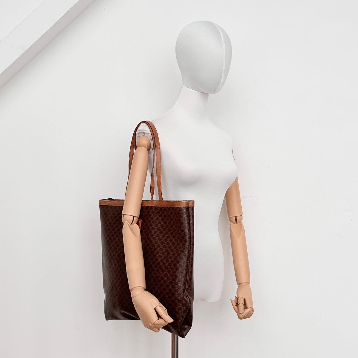 Front view of the Celine Triomphe Macadam Tote Bag in brown coated canvas with tan leather detailing and double handles.