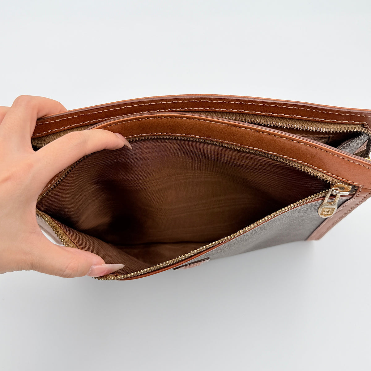 Celine Triomphe Macadam Clutch Bag in brown coated canvas with tan leather trim and gold zip, displayed against a white background.