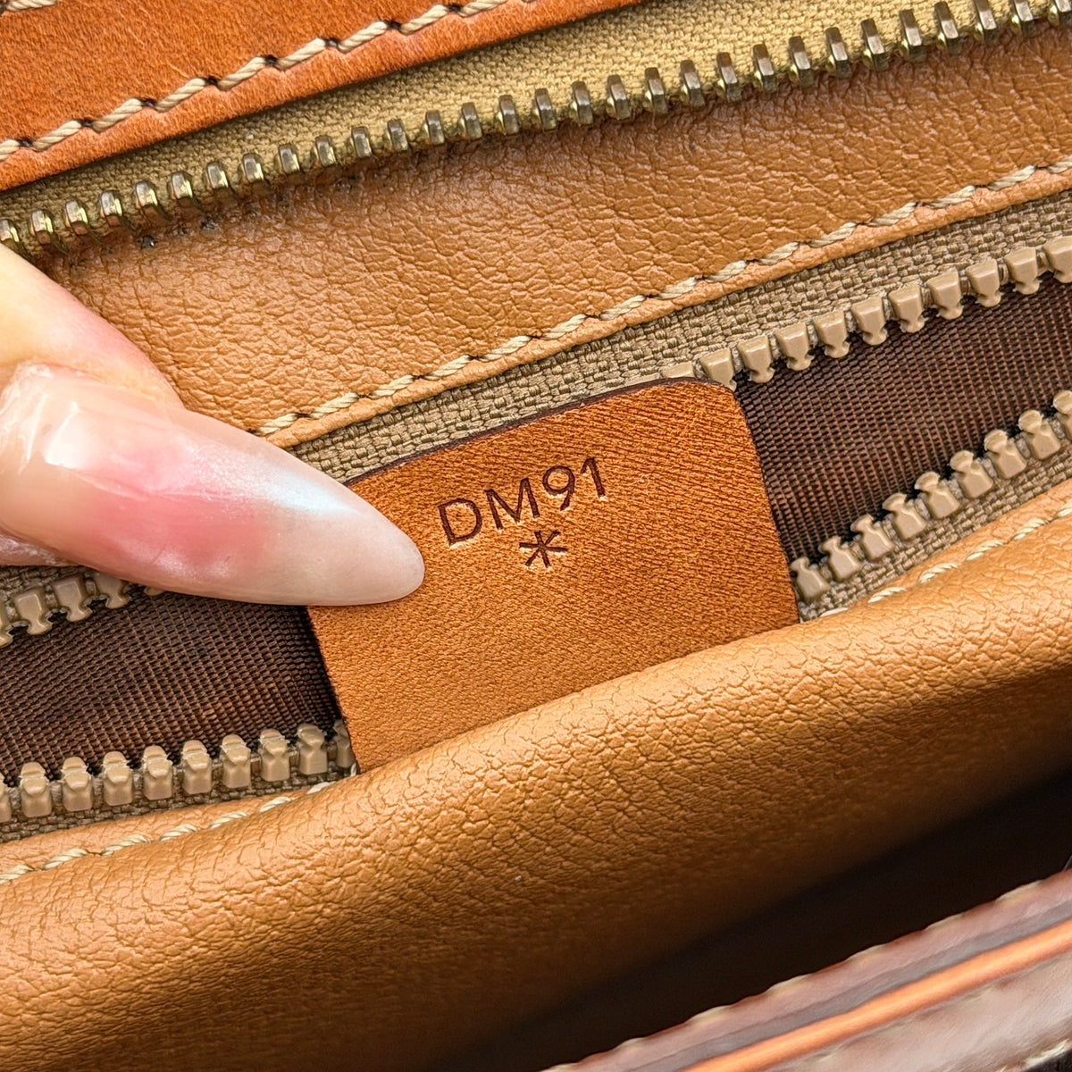 Celine Triomphe Macadam Clutch Bag in brown coated canvas with tan leather trim and gold zip, displayed against a white background.