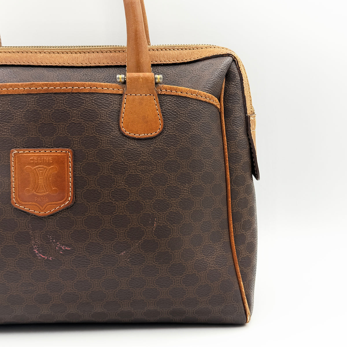 Celine Triomphe Macadam Boston Bag in brown coated canvas with tan leather trim and top handles, photographed against a white background.